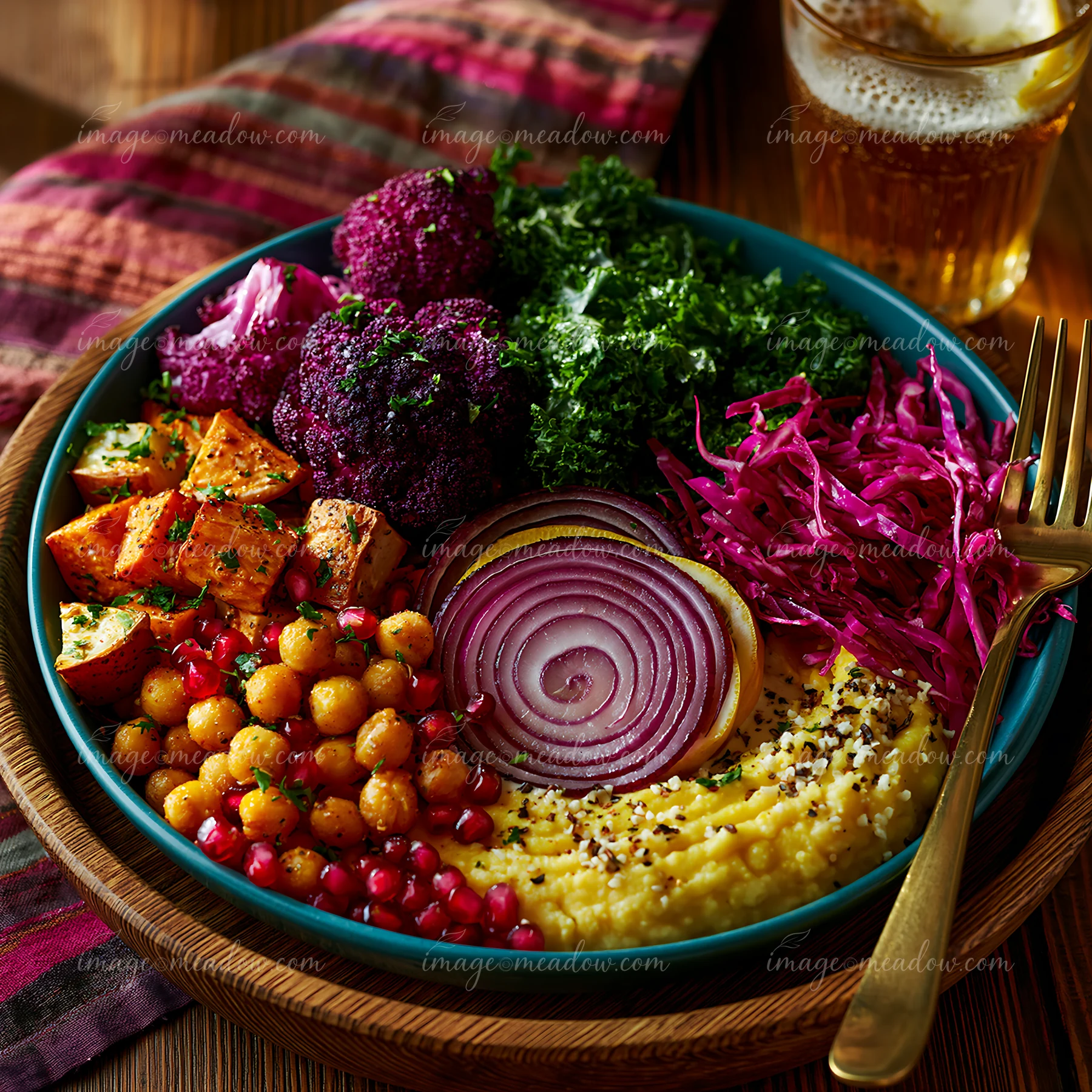 A bowl contains roasted vegetables, legumes, and garnishes, displayed artfully.