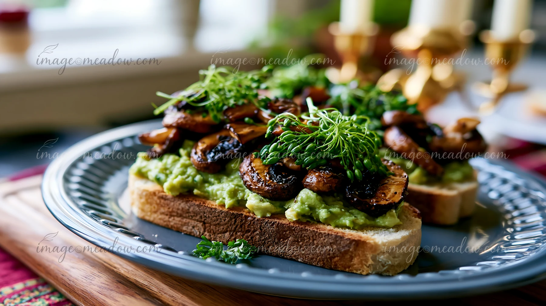 A breakfast plate features toasted bread topped with mashed avocado and sautéed mushrooms.