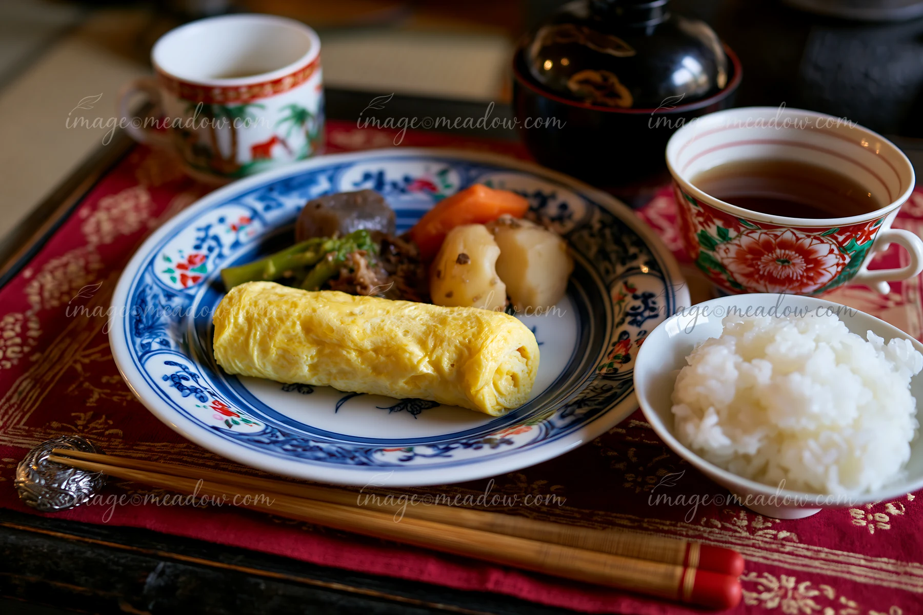 A breakfast plate with Japanese breakfast includes rice, omelette, and side dishes.
