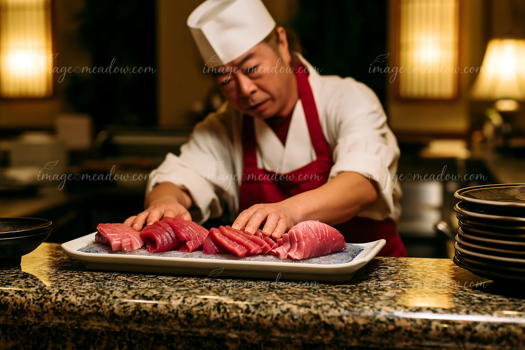 A chef preparing sushi at restaurant counter works with fresh fish and neatly places slices on a platter.