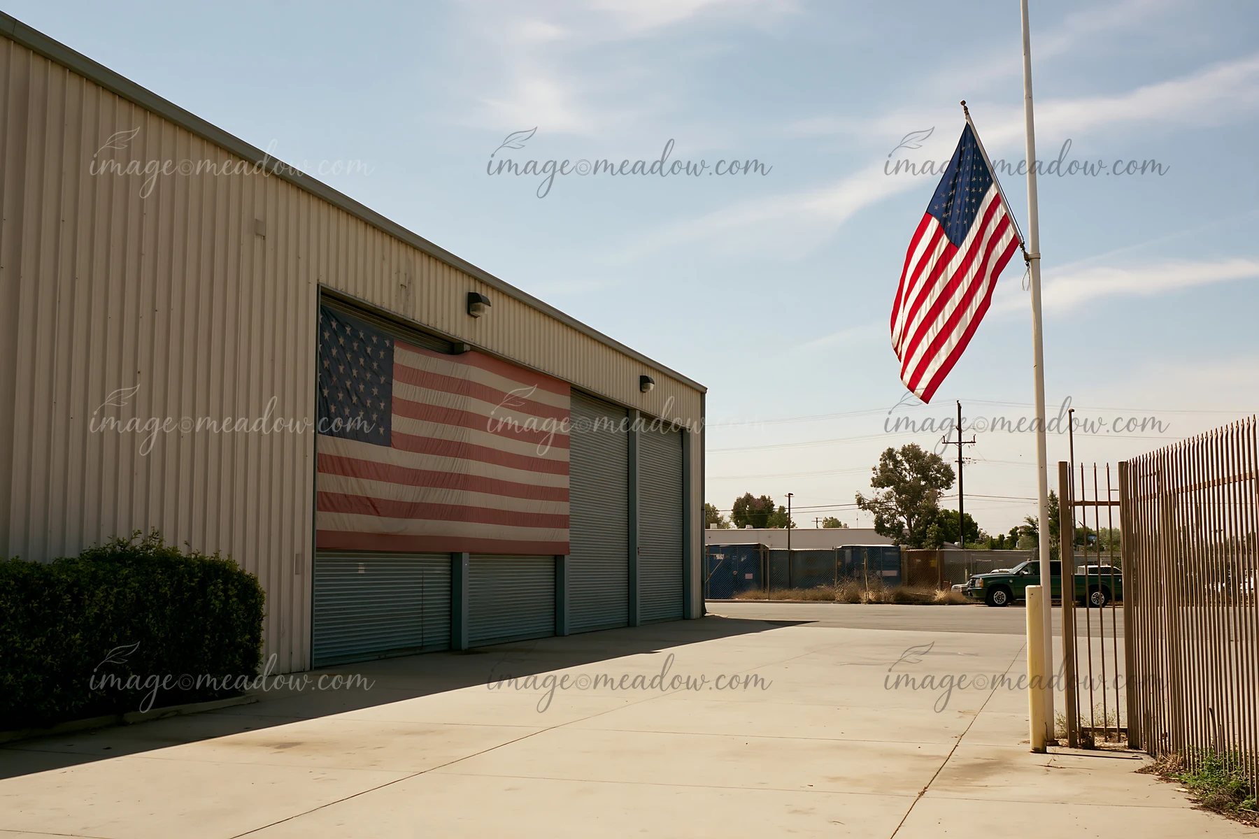 An American flag waves outside a factory where another large flag is displayed on the wall.