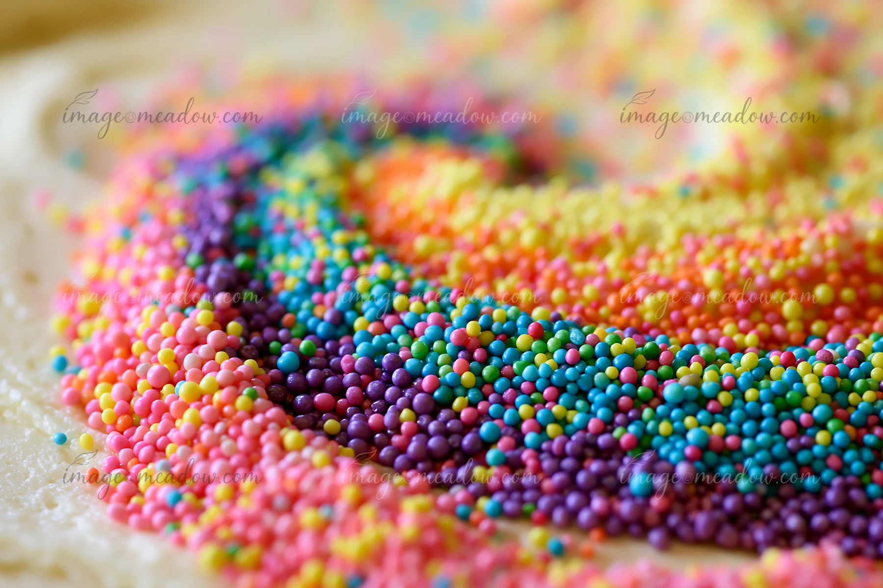 Rainbow sprinkles arranged in a swirl create a colorful pattern on a dessert surface.