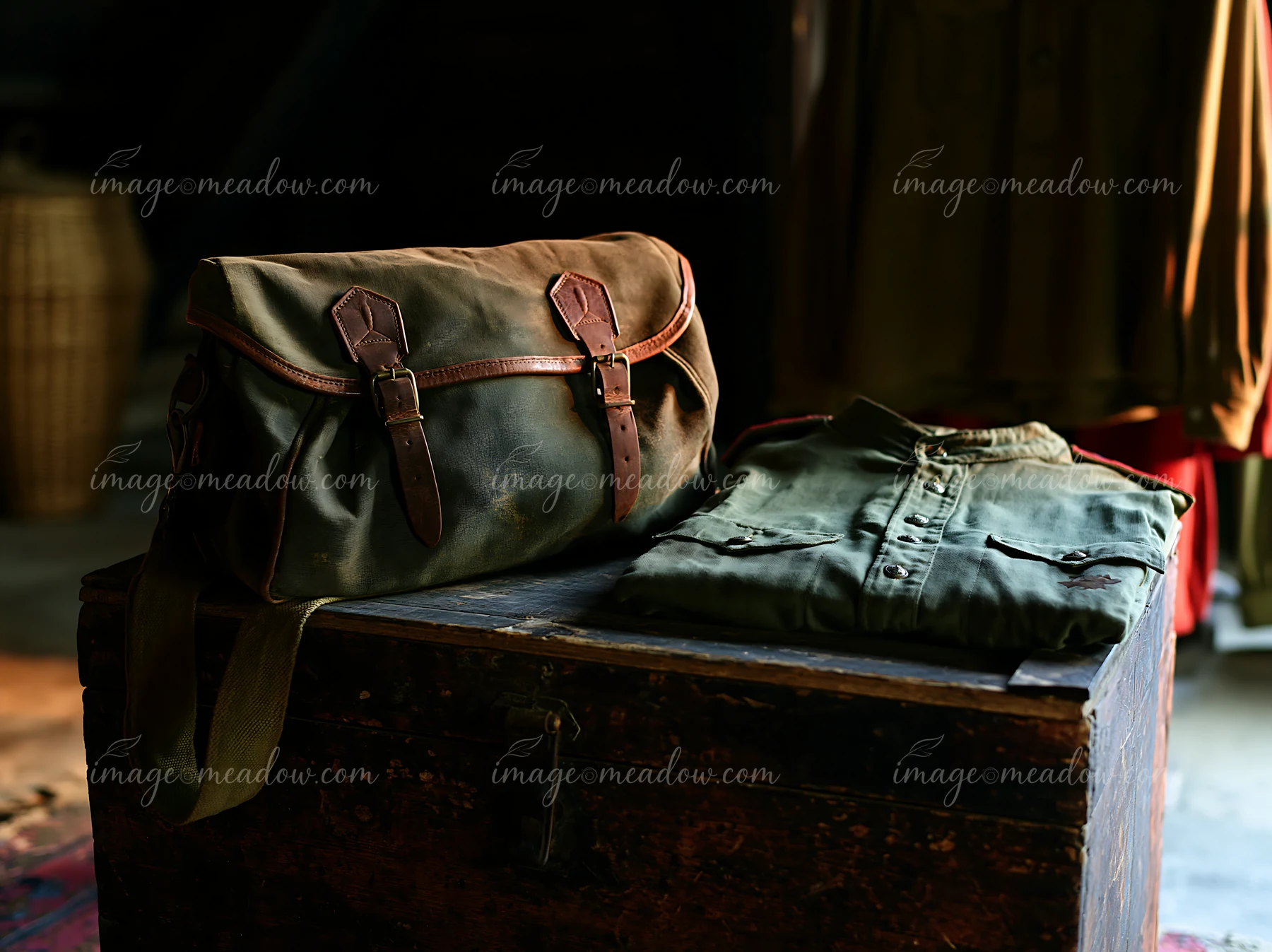 A brown bag and a folded shirt lie on a wooden table in a dimly lit room.