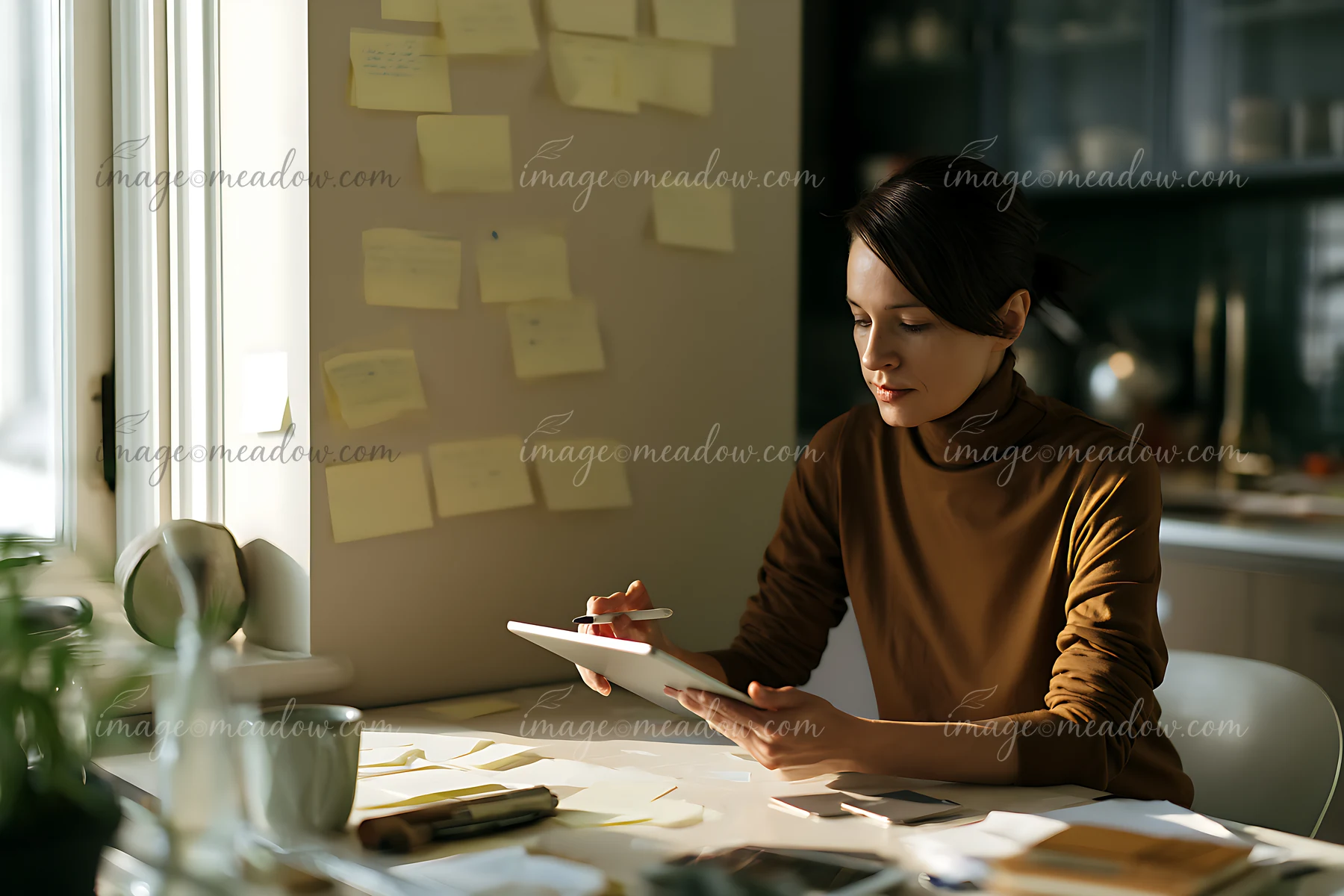 A businesswoman examines her project timeline on a tablet in a modern office.