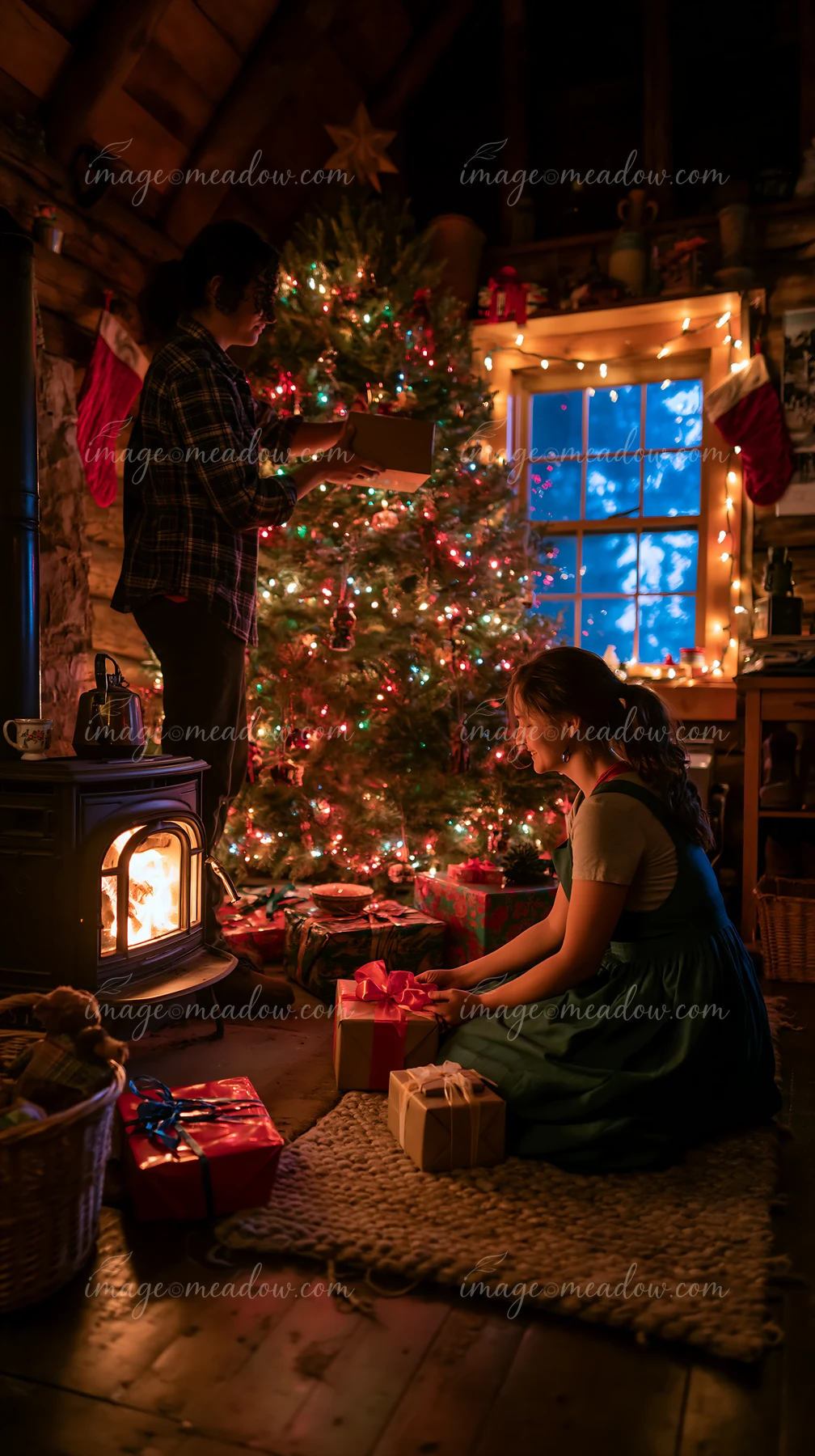 A child sits near the fireplace while a parent places gifts under the decorated Christmas tree.