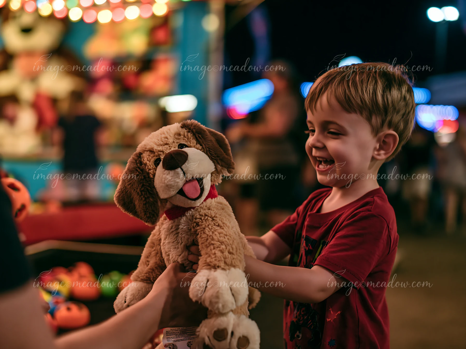 A child smiles while holding a stuffed animal received at a fair booth.