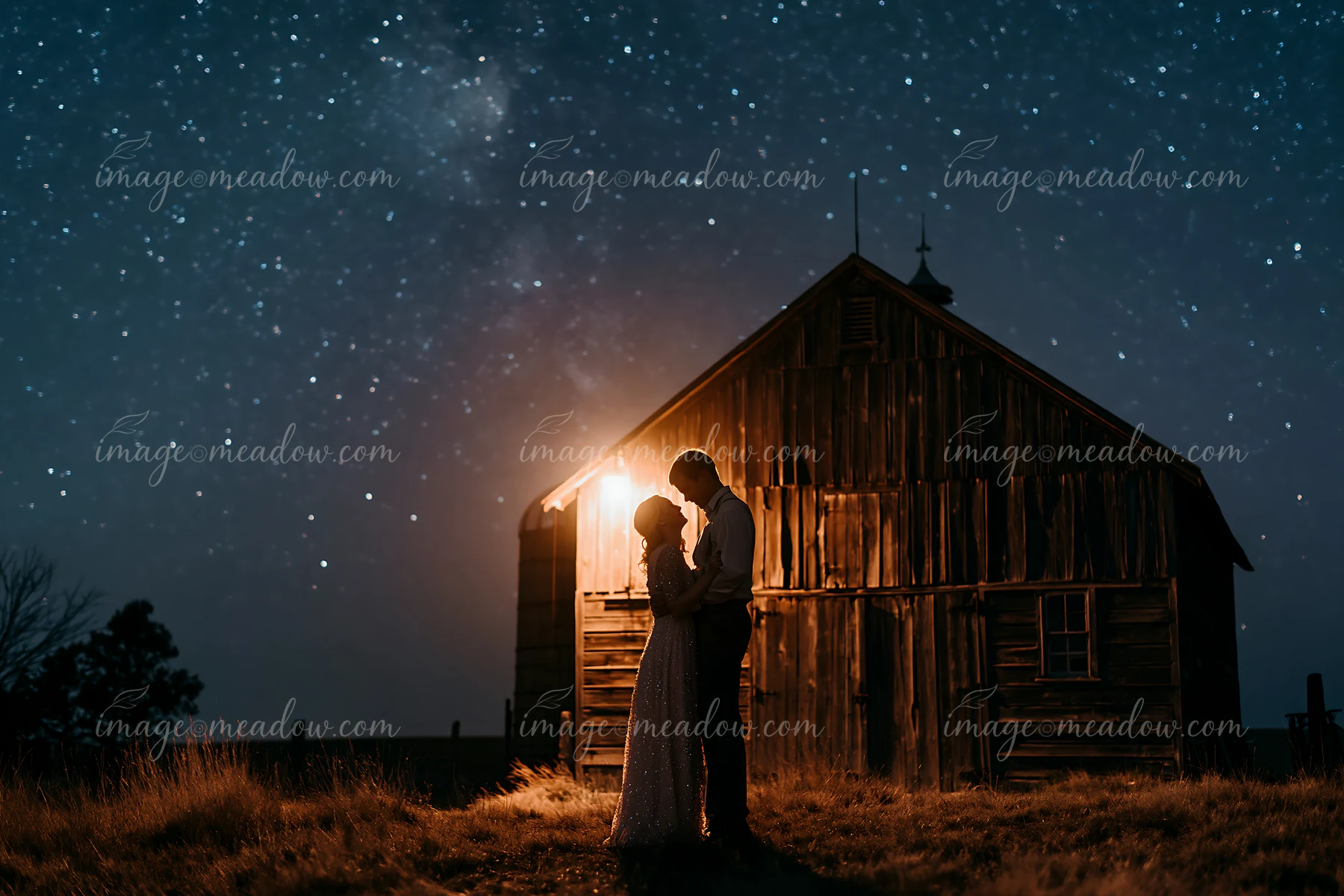 A couple dancing under stars outdoors near a rustic barn.