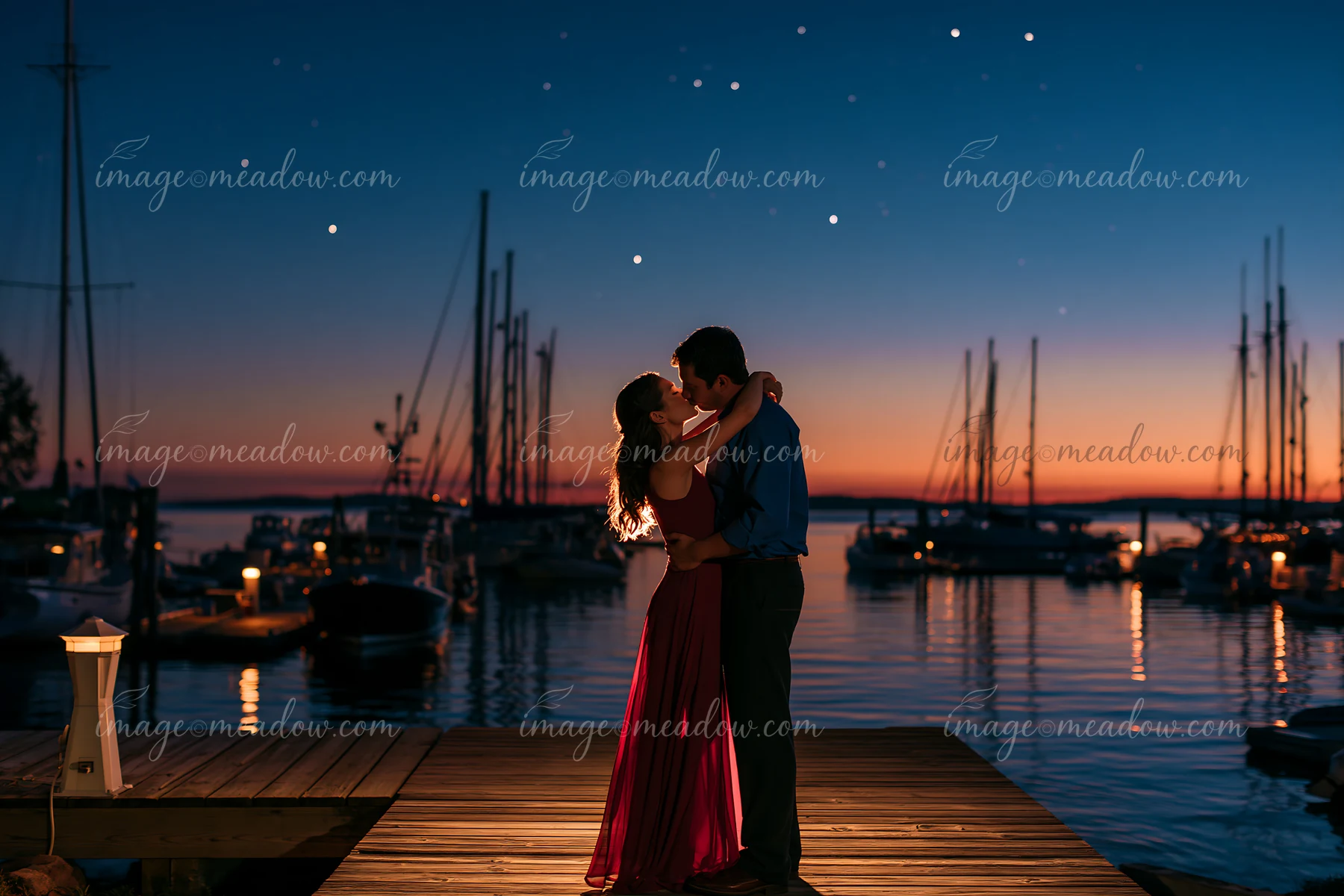 A couple kissing on a dock under stars, surrounded by boats and a glowing sunset in the background.