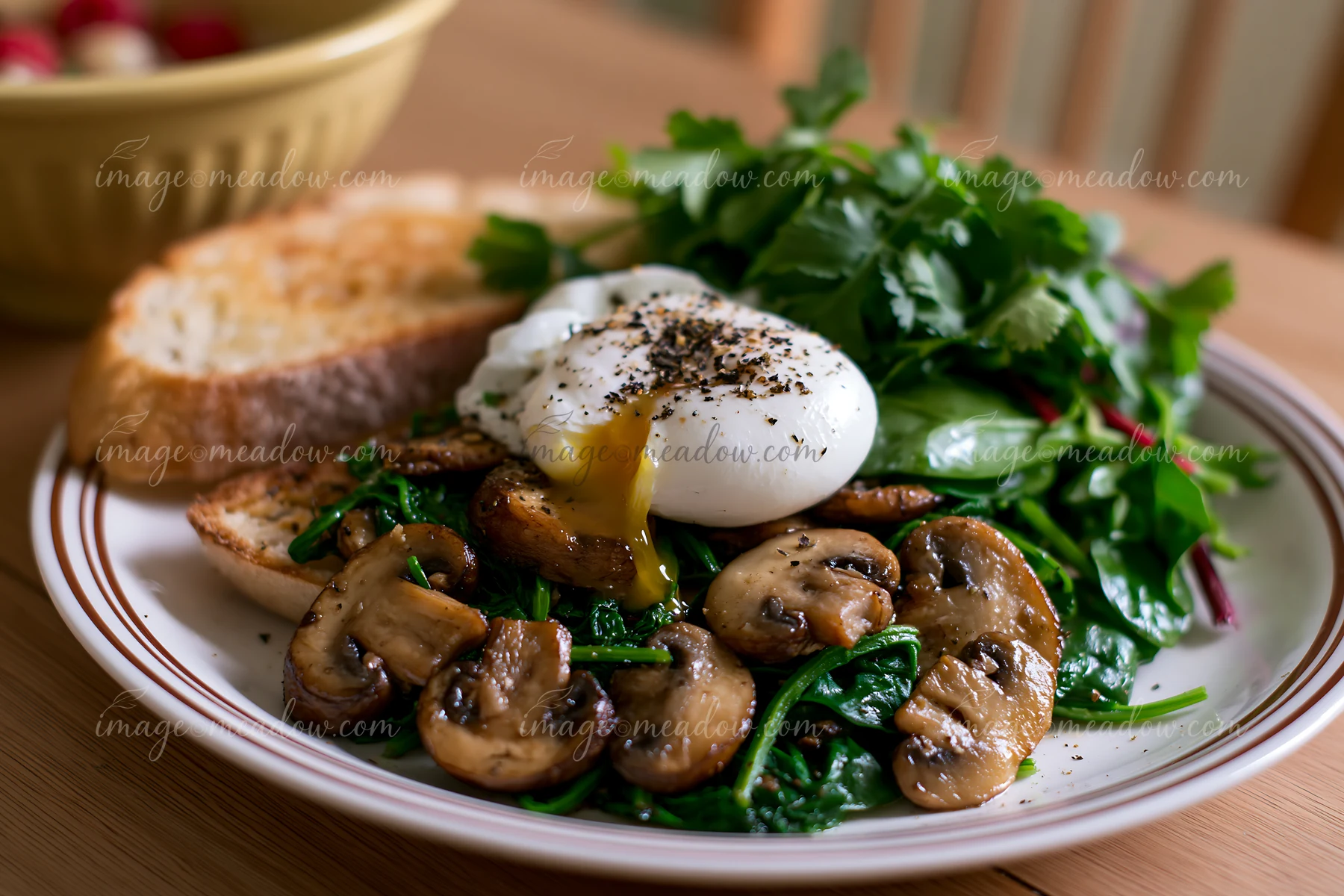 A healthy breakfast plate on wooden table includes poached eggs, sautéed mushrooms, and fresh greens served with toasted bread.
