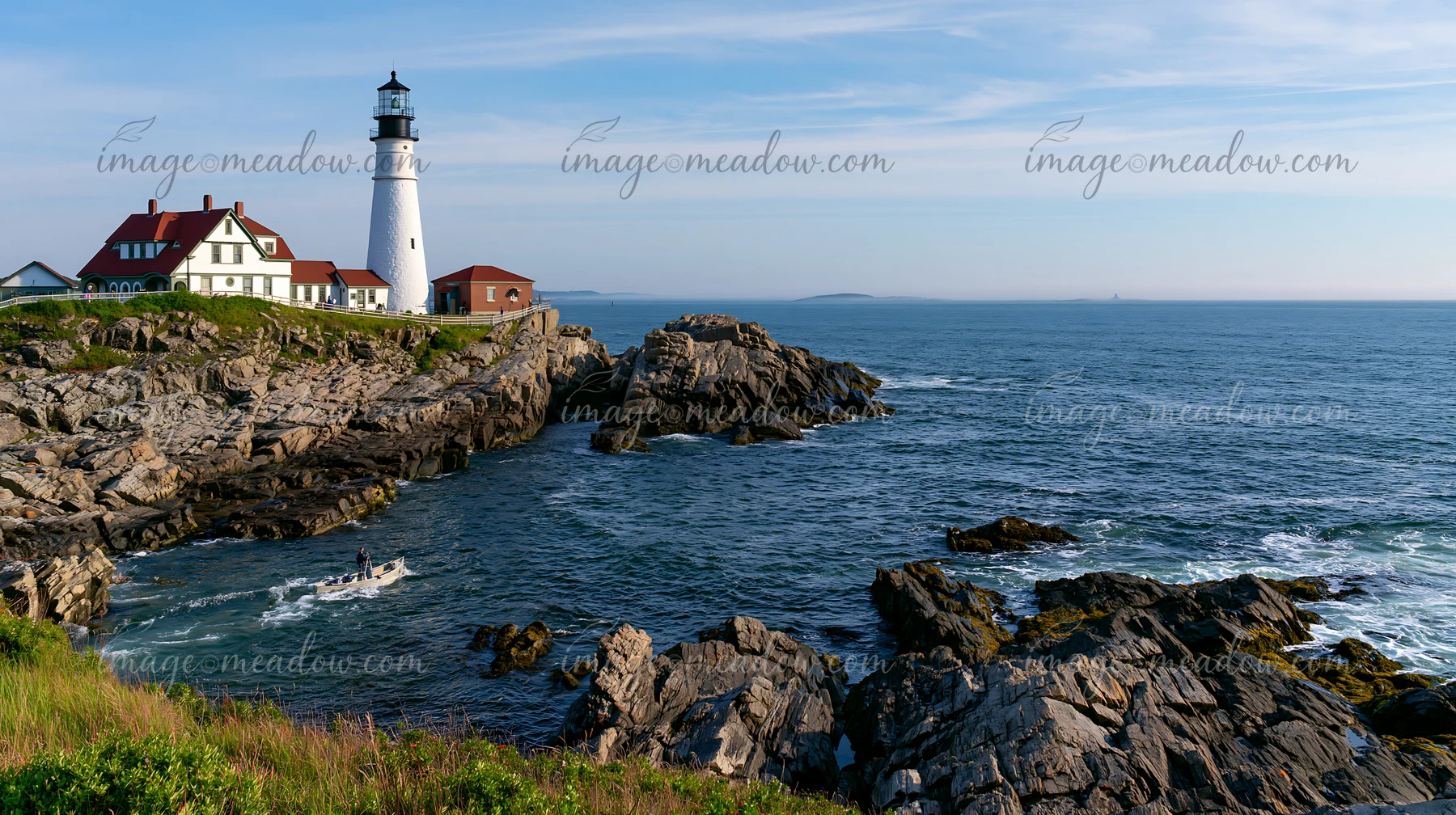 A lighthouse near a rocky tide pool stands against the backdrop of the sea.
