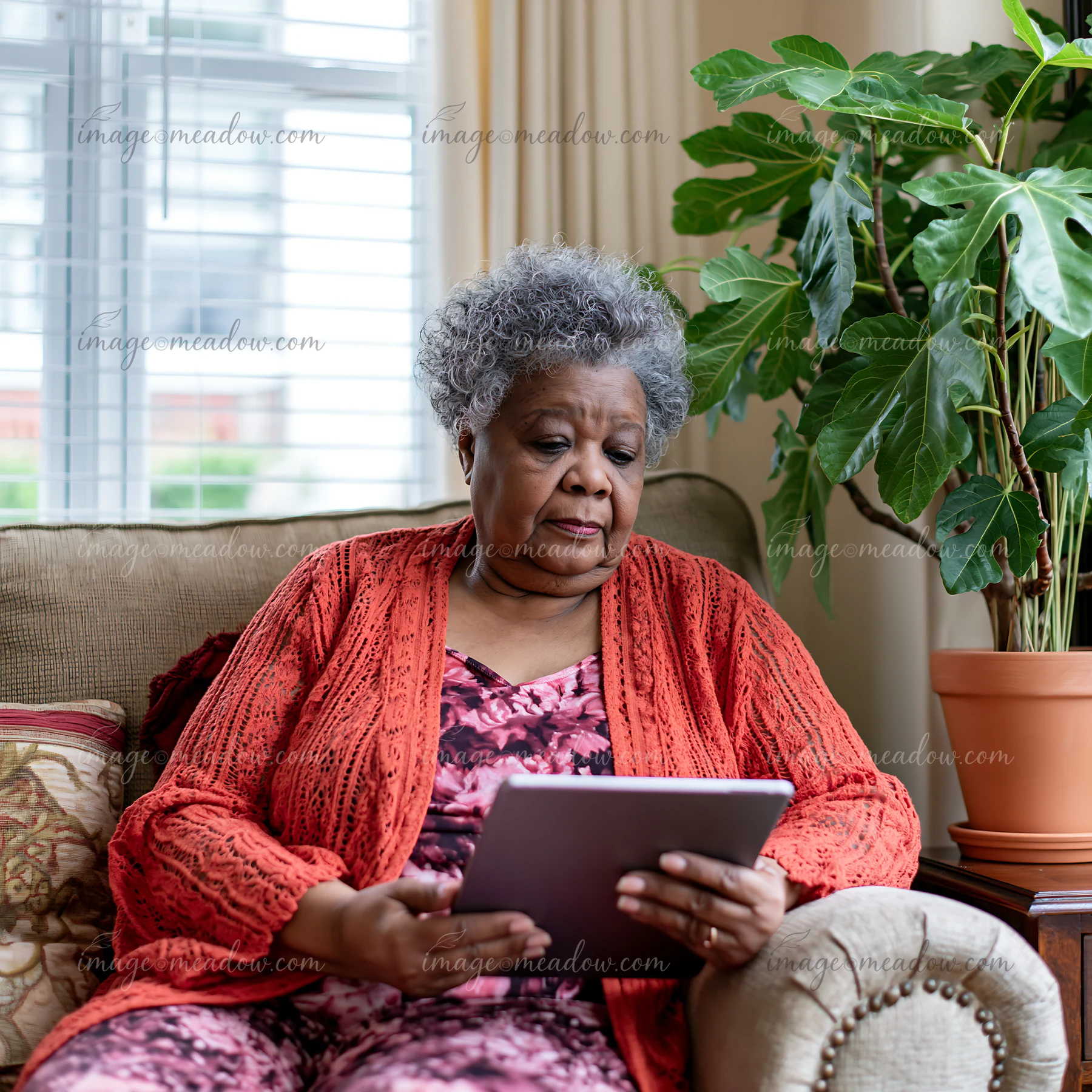 A Parkinson's patient is sitting on a sofa at home, using a tablet.