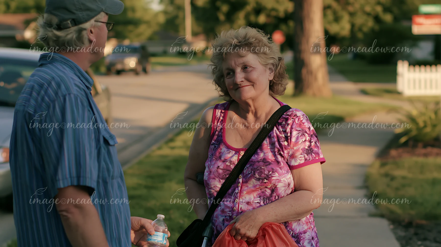 A person with Parkinson's disease receiving support from another person on a sunny day in a neighborhood.