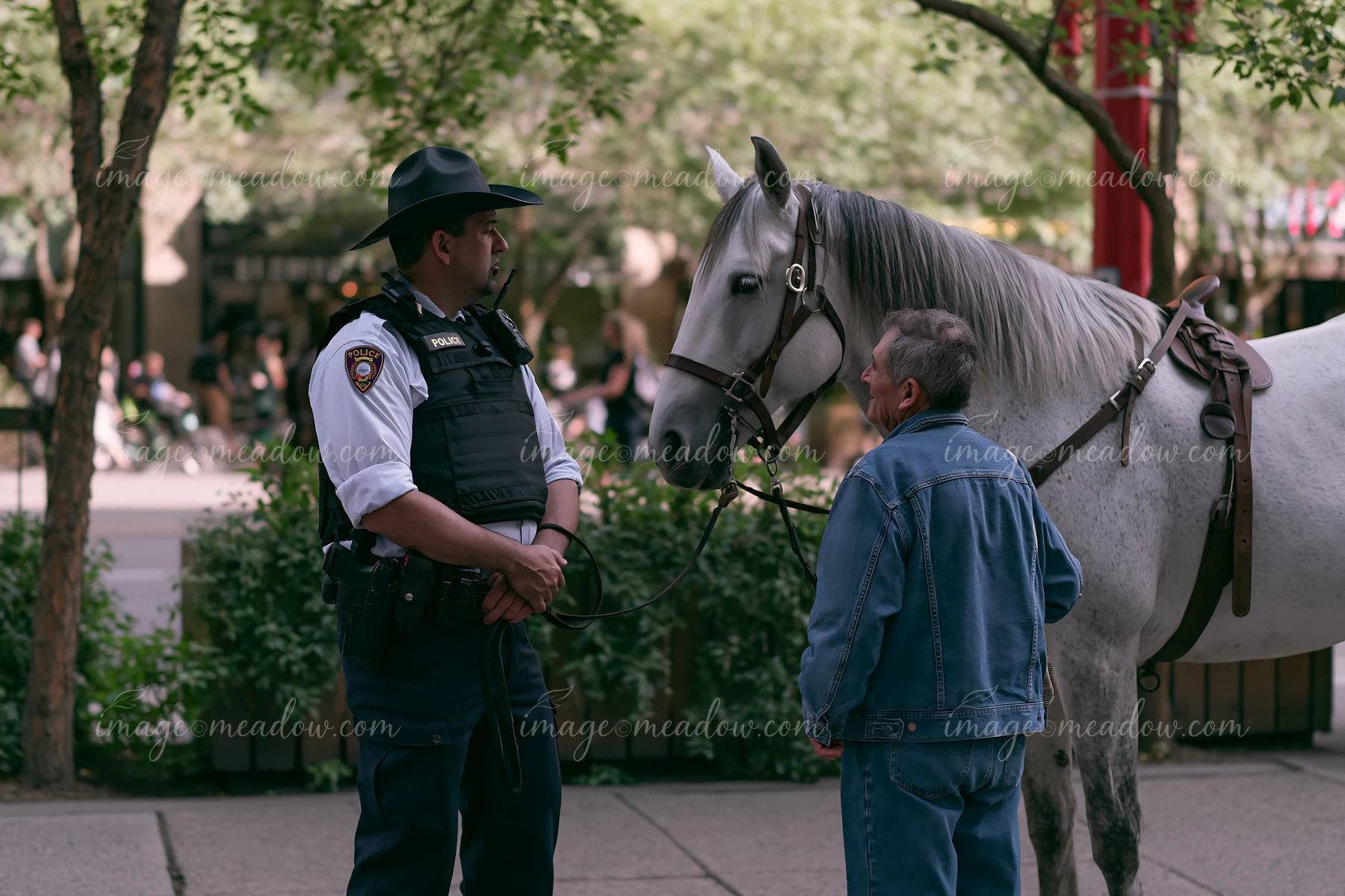 A police officer speaks with a citizen while on horseback in a bustling city setting.