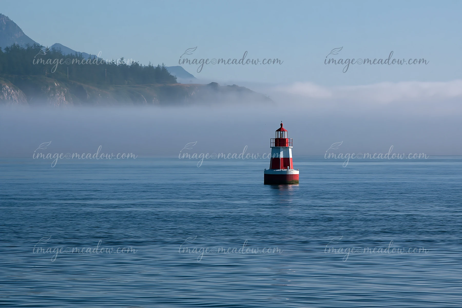 A red and white lighthouse stands in the water, surrounded by a thick sea fog.