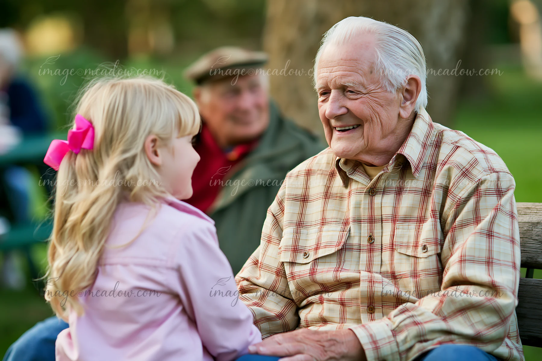 A senior man interacts with a young girl in a park setting.