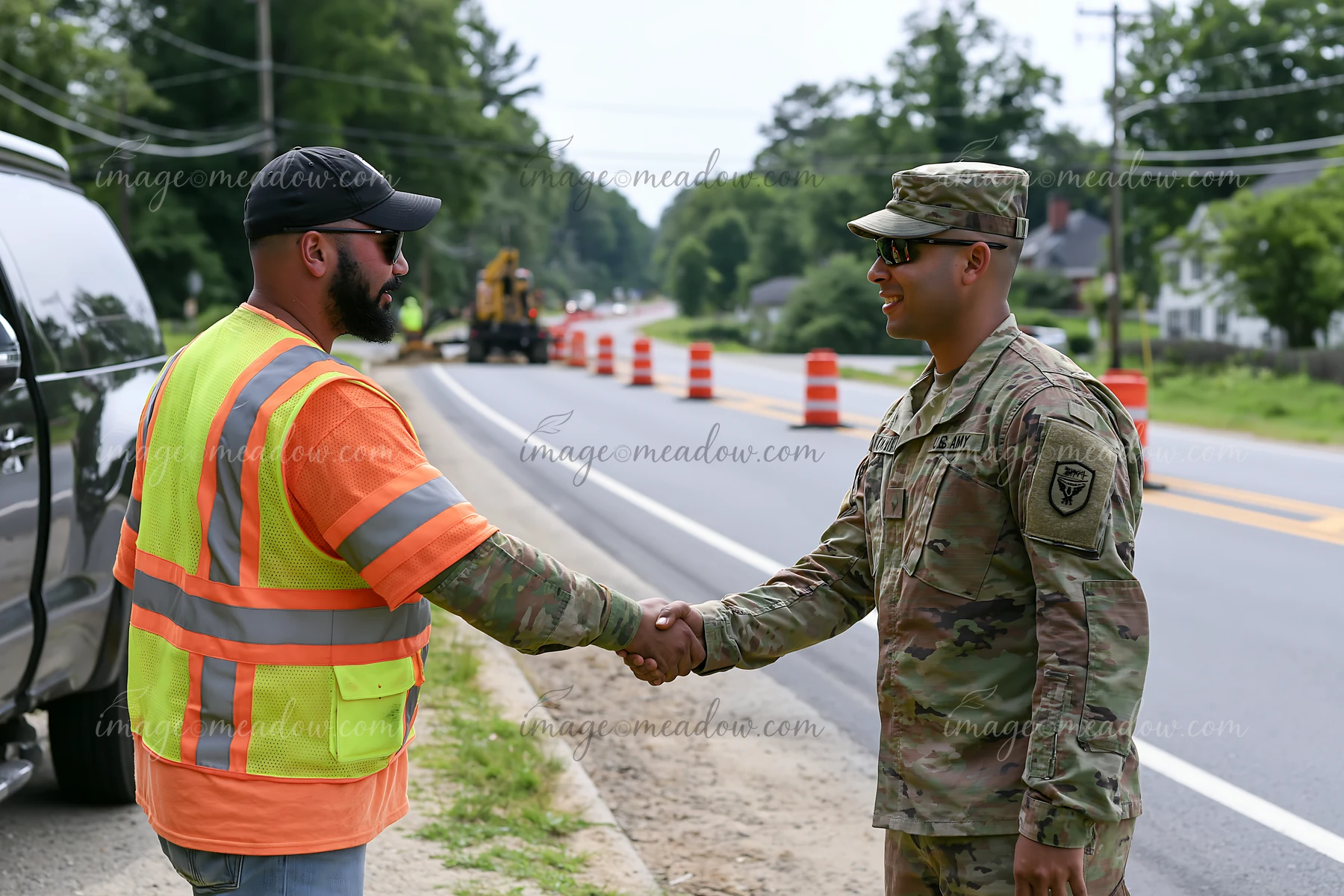 A soldier shaking hands with a construction worker beside a busy road.