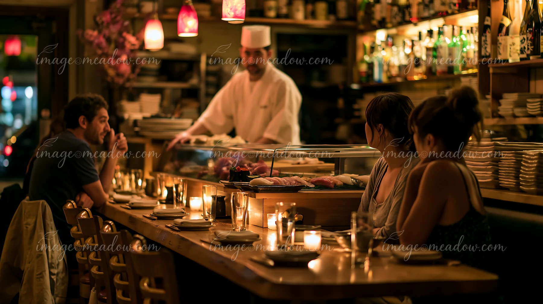 A sushi chef greeting diners in a lively restaurant while preparing dishes.