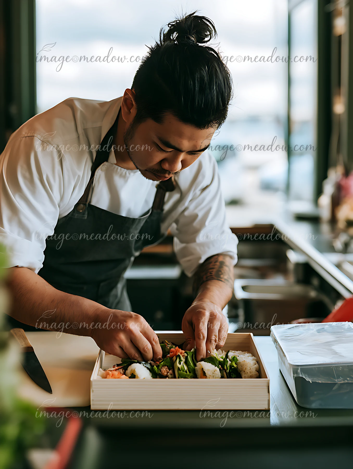 A sushi chef prepares a lunch box by carefully packing fresh sushi.