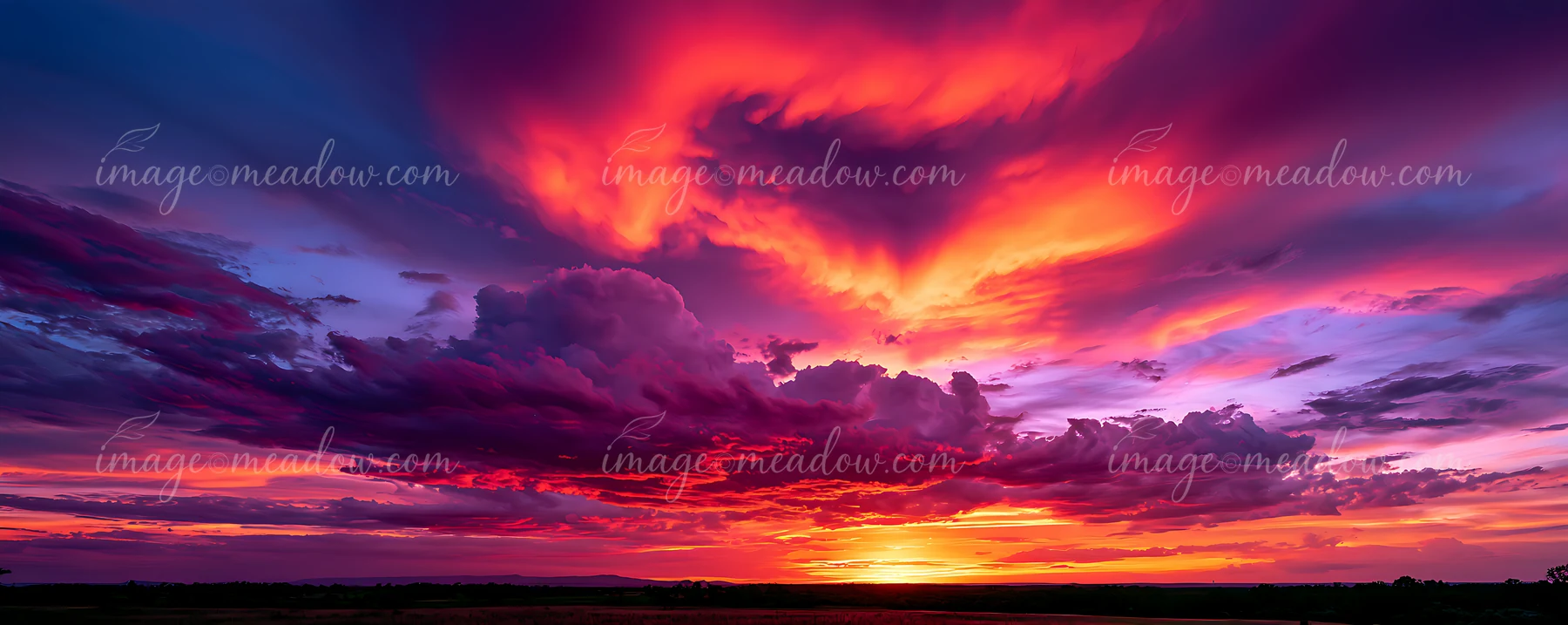 Bold colors fill the sky as the sun sets, casting orange, pink, and purple hues across the landscape.