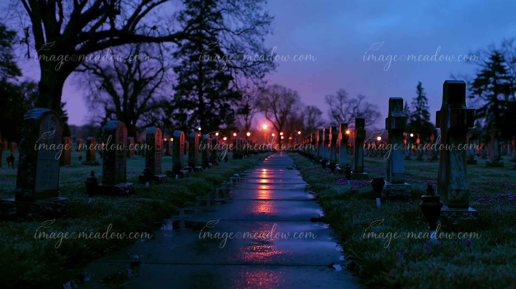 Graves of soldiers are seen in a cemetery at night, surrounded by trees and illuminated by soft lights.