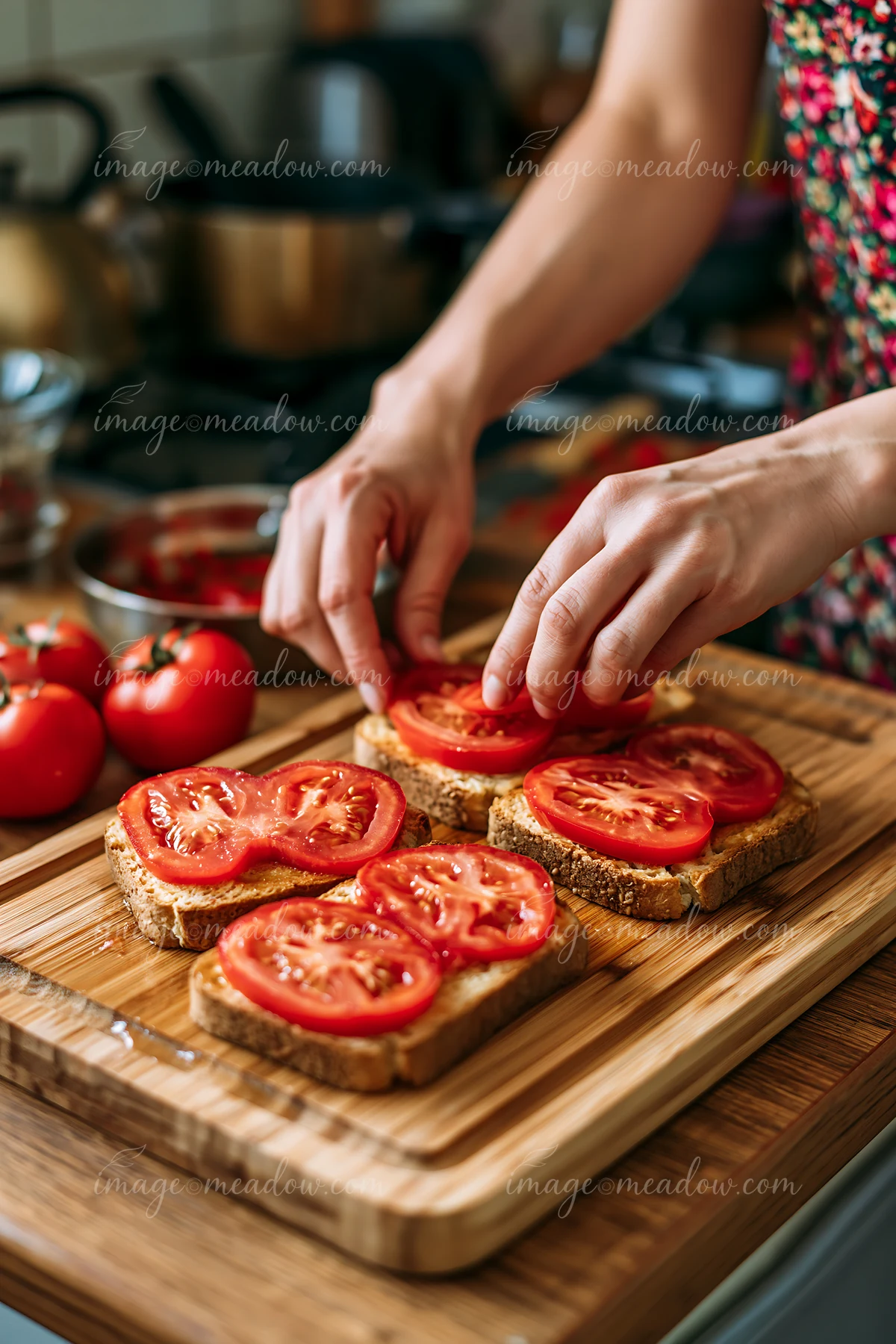 Hands prepare heart-shaped tomato slices on toasted bread in a kitchen.