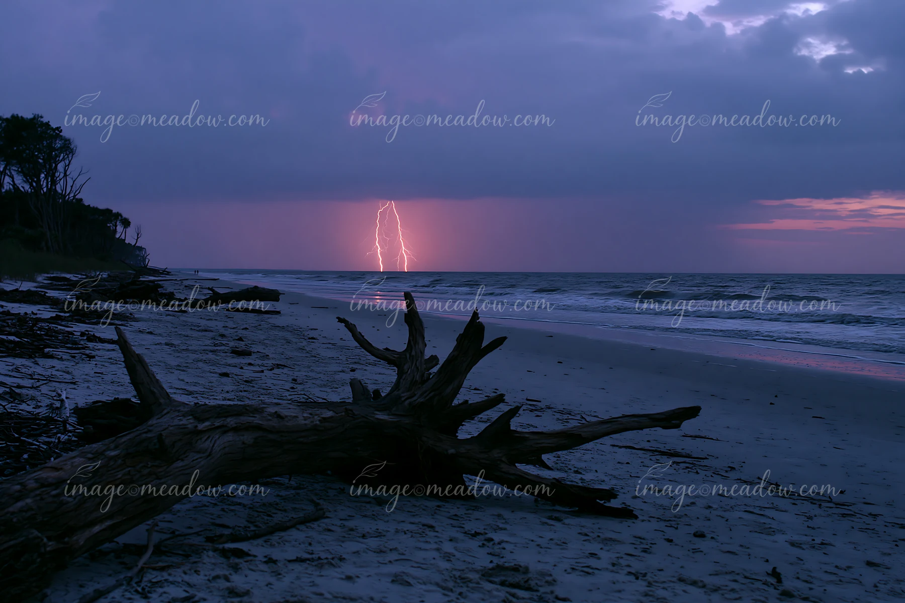 Lightning strikes over the ocean as dark clouds gather at dusk.