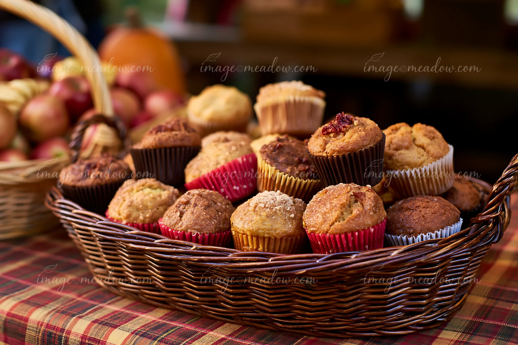 Muffins of various flavors are arranged in a basket at a seasonal market setting.