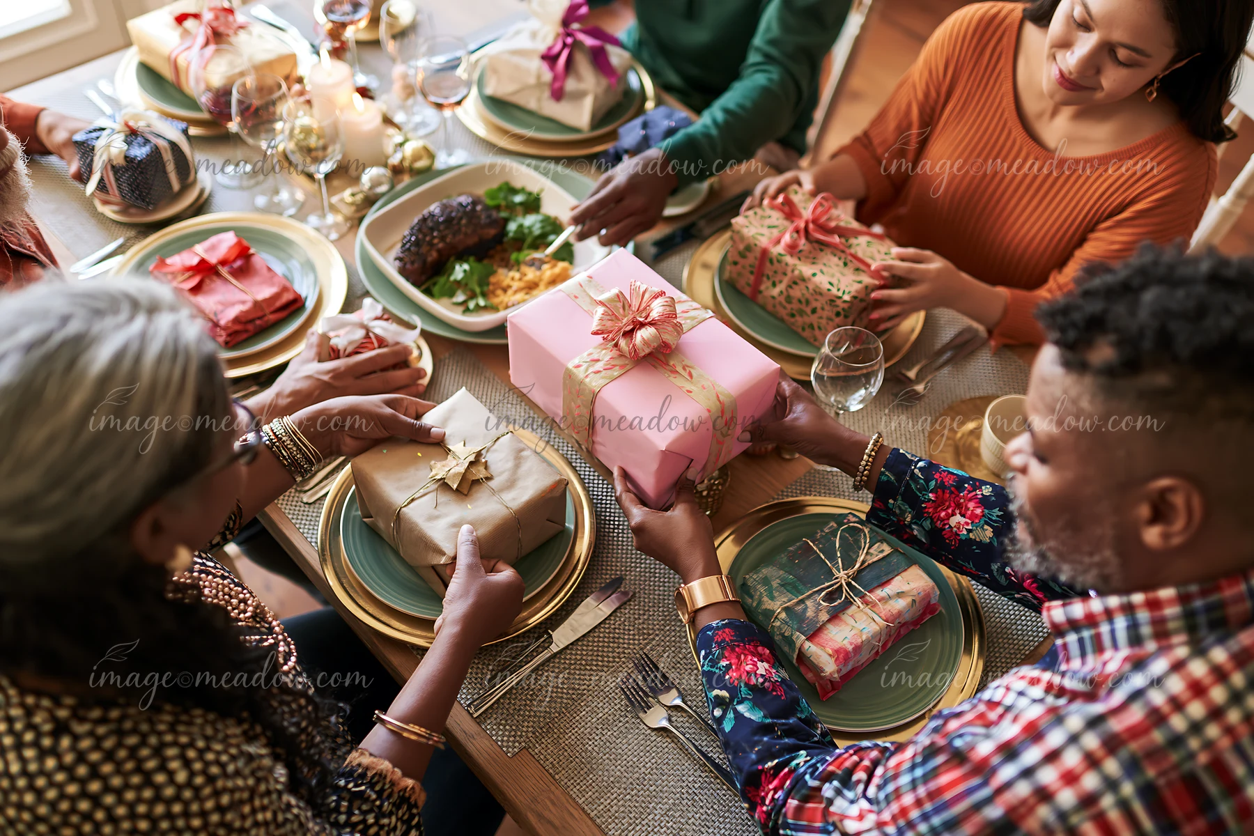 Parents arrange wrapped gifts around a dining table set for a festive family meal.
