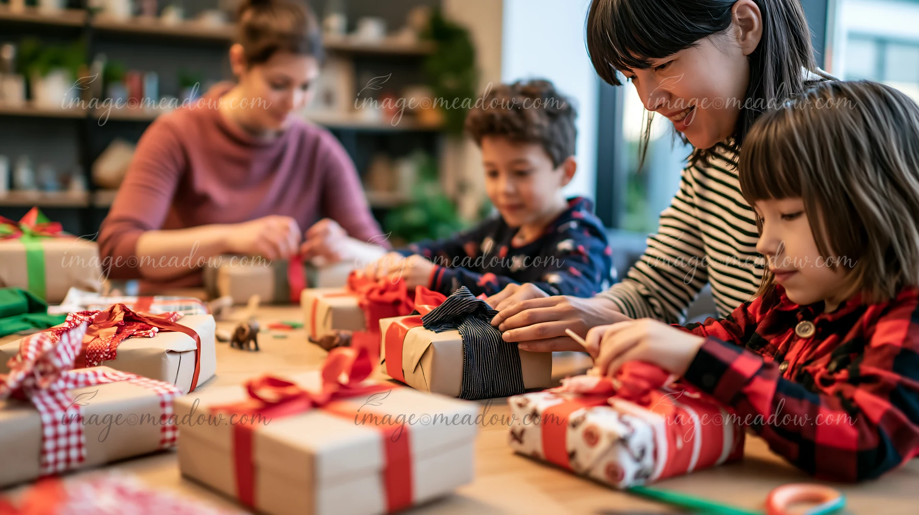 Parents help two children wrap presents at a table covered with colorful gift boxes and ribbons.