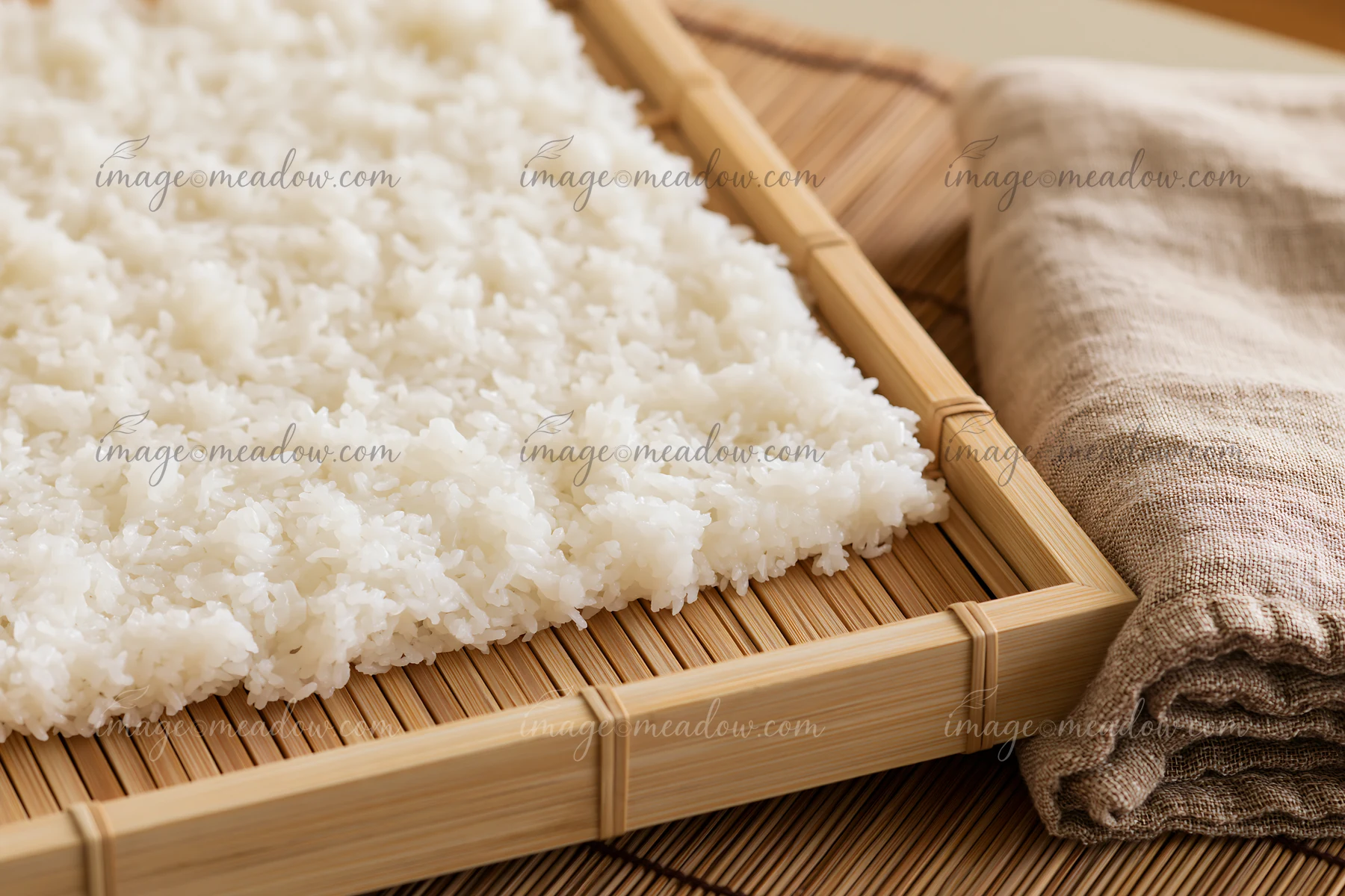 Sushi rice cooling on tray after cooking is spread evenly to help reduce steam and moisture.