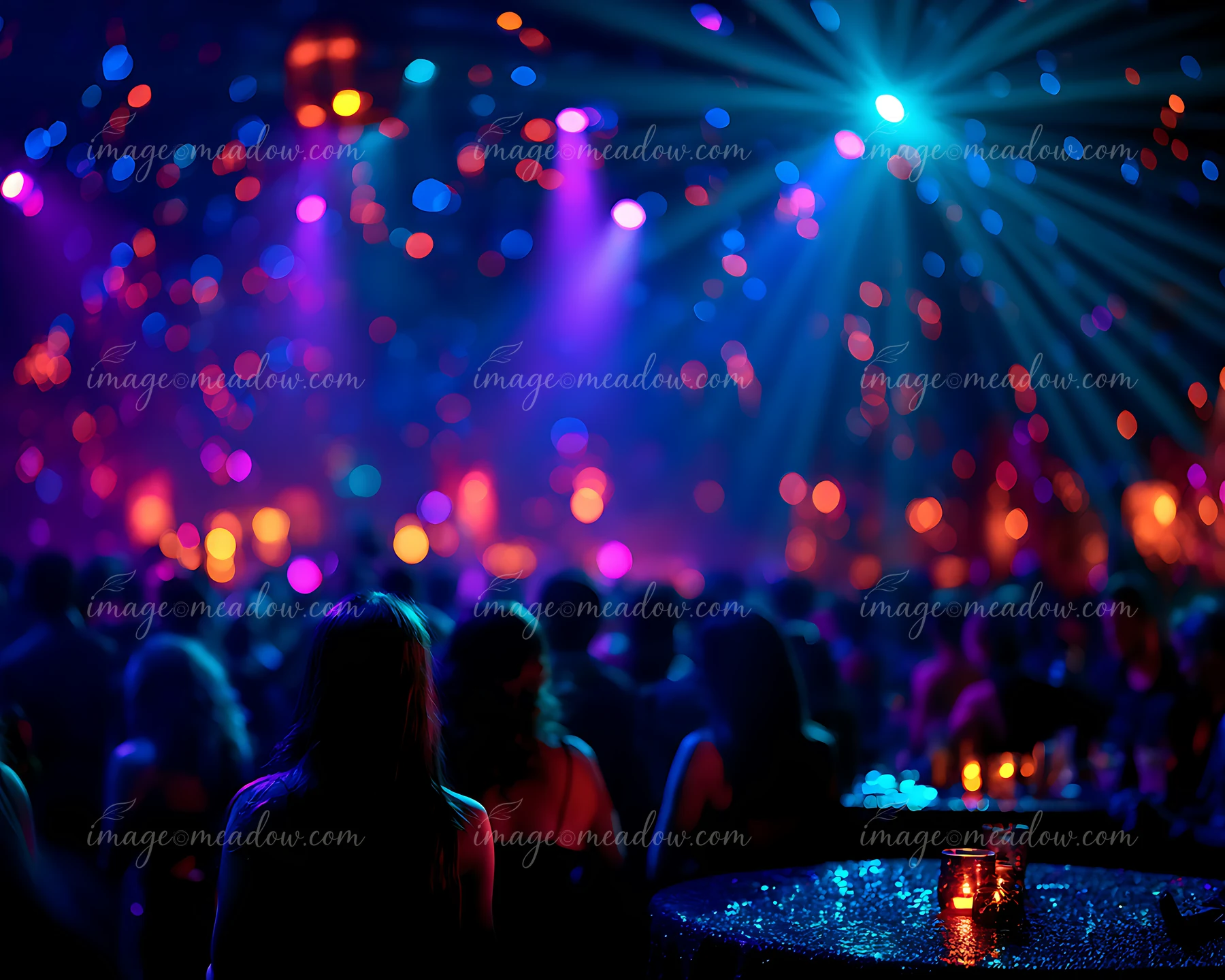 The scene shows a vibrant dance floor filled with people enjoying music and dancing under colorful lights.