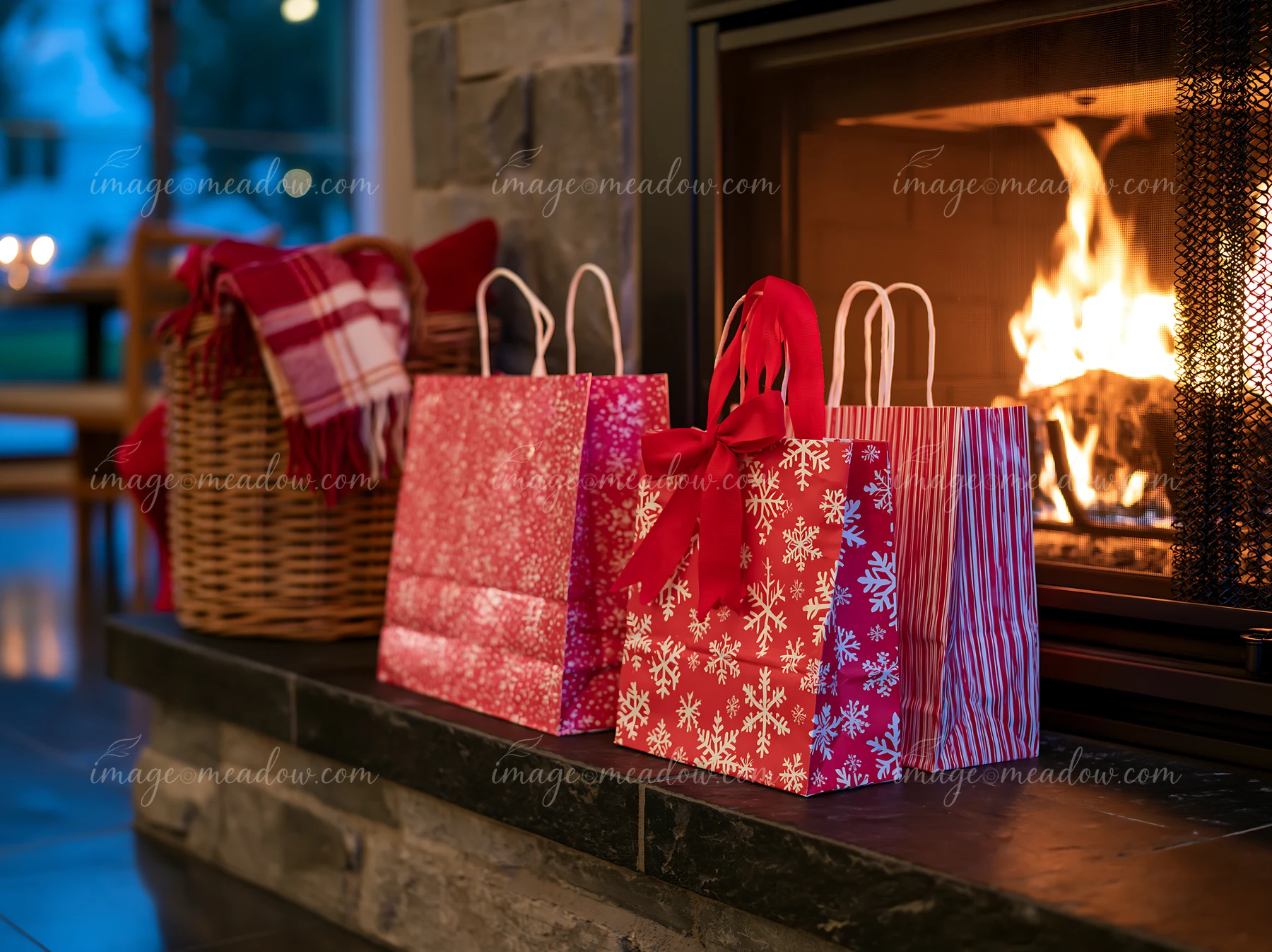 Three holiday shopping bags are placed beside a fireplace in a cozy living room.