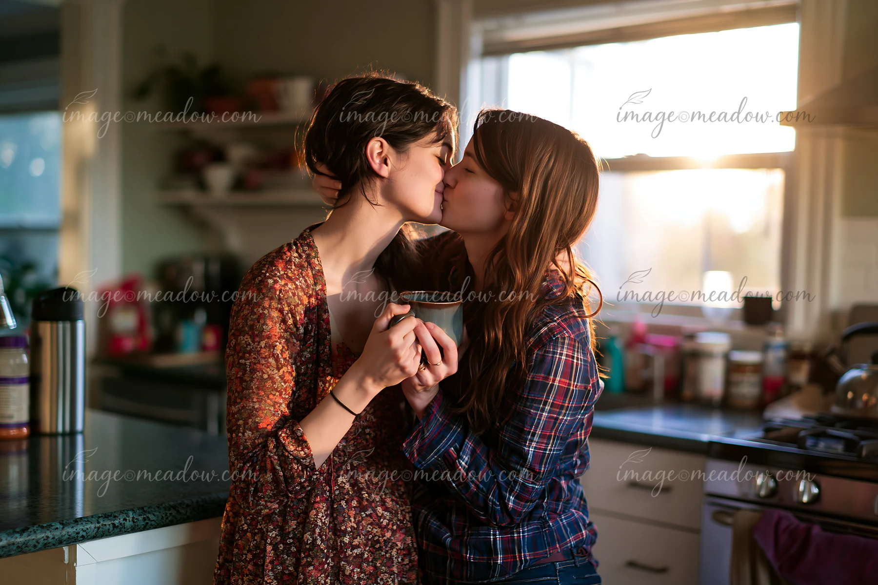 Two partners kiss in a cozy kitchen filled with warm light from the sunset.