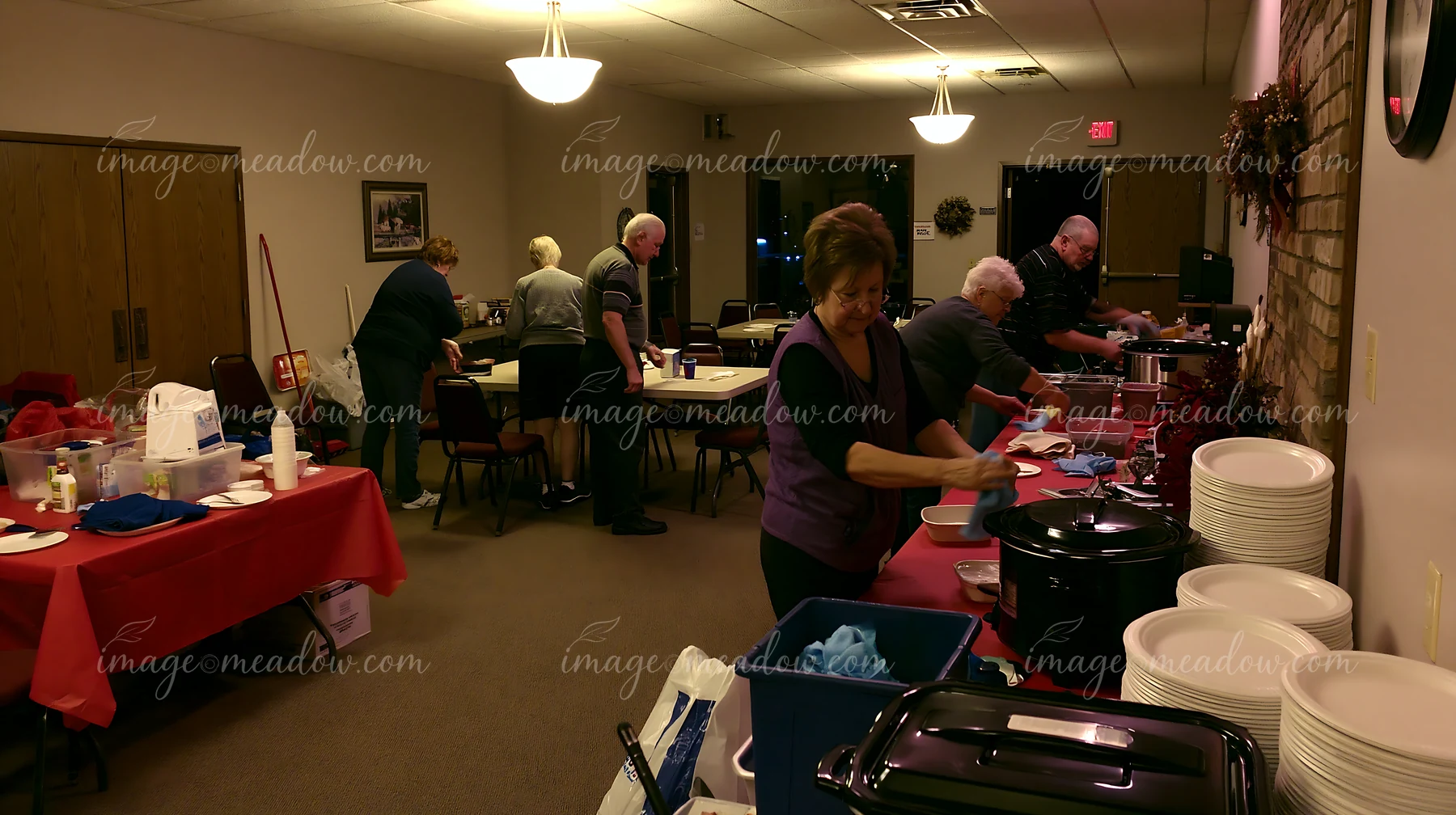 Volunteers are setting up a buffet for a charity event in a community hall.