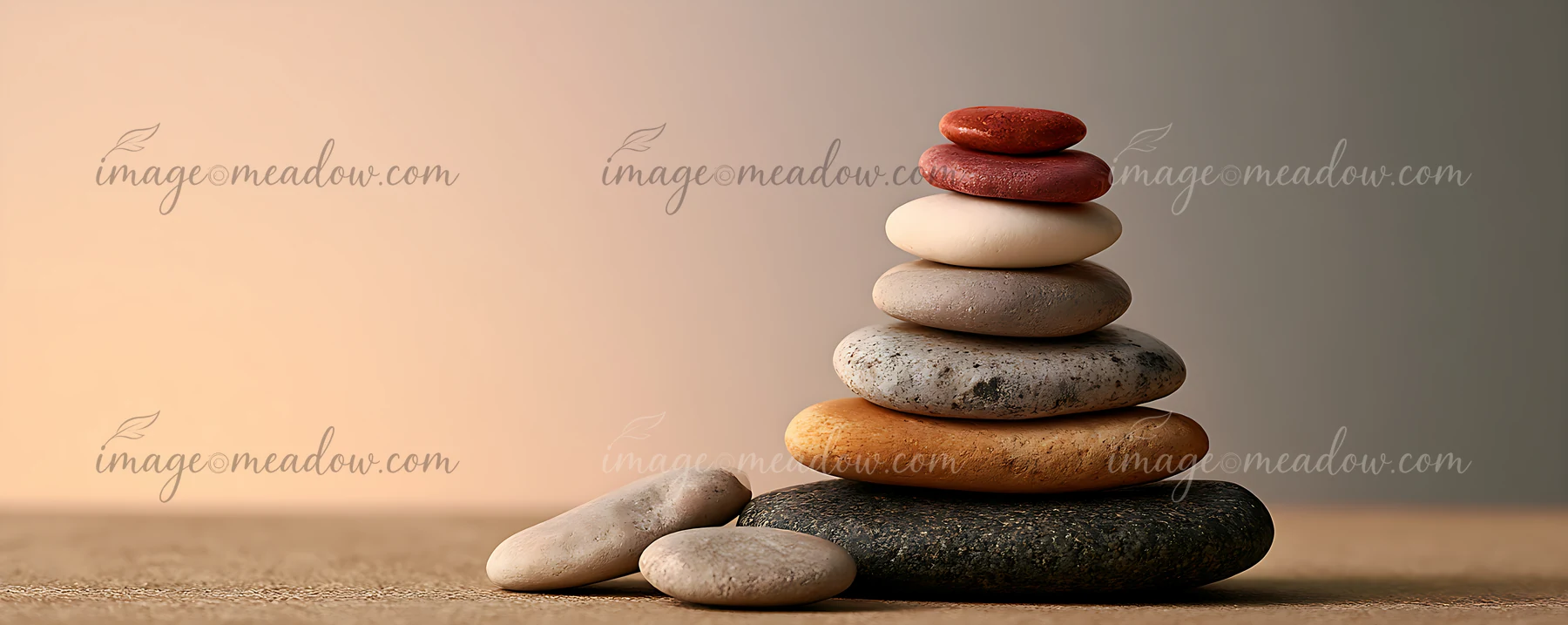 A balanced arrangement of smooth stones includes various colors and sizes, resting on a flat surface with a blurred background.