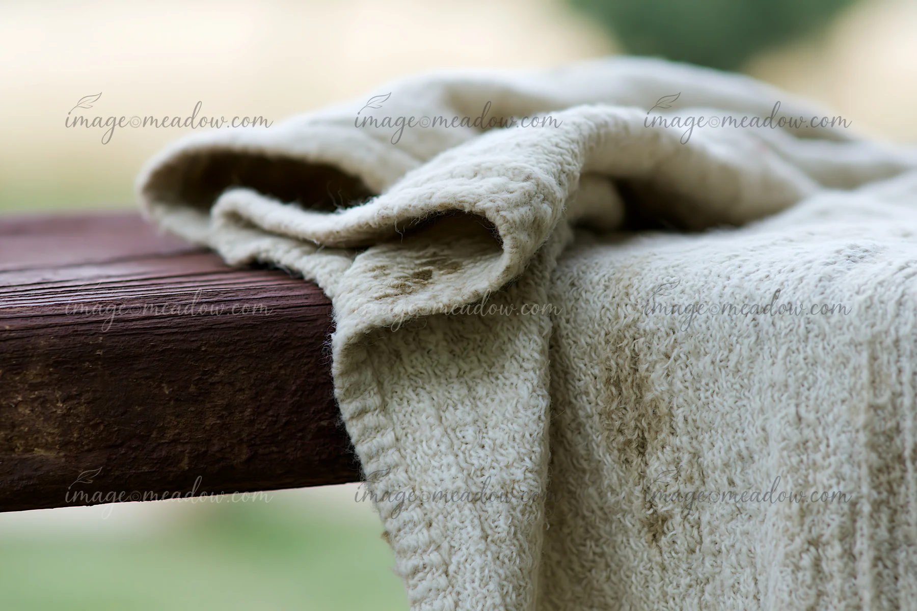 A beige fabric texture with faded blotches rests on a wooden surface.