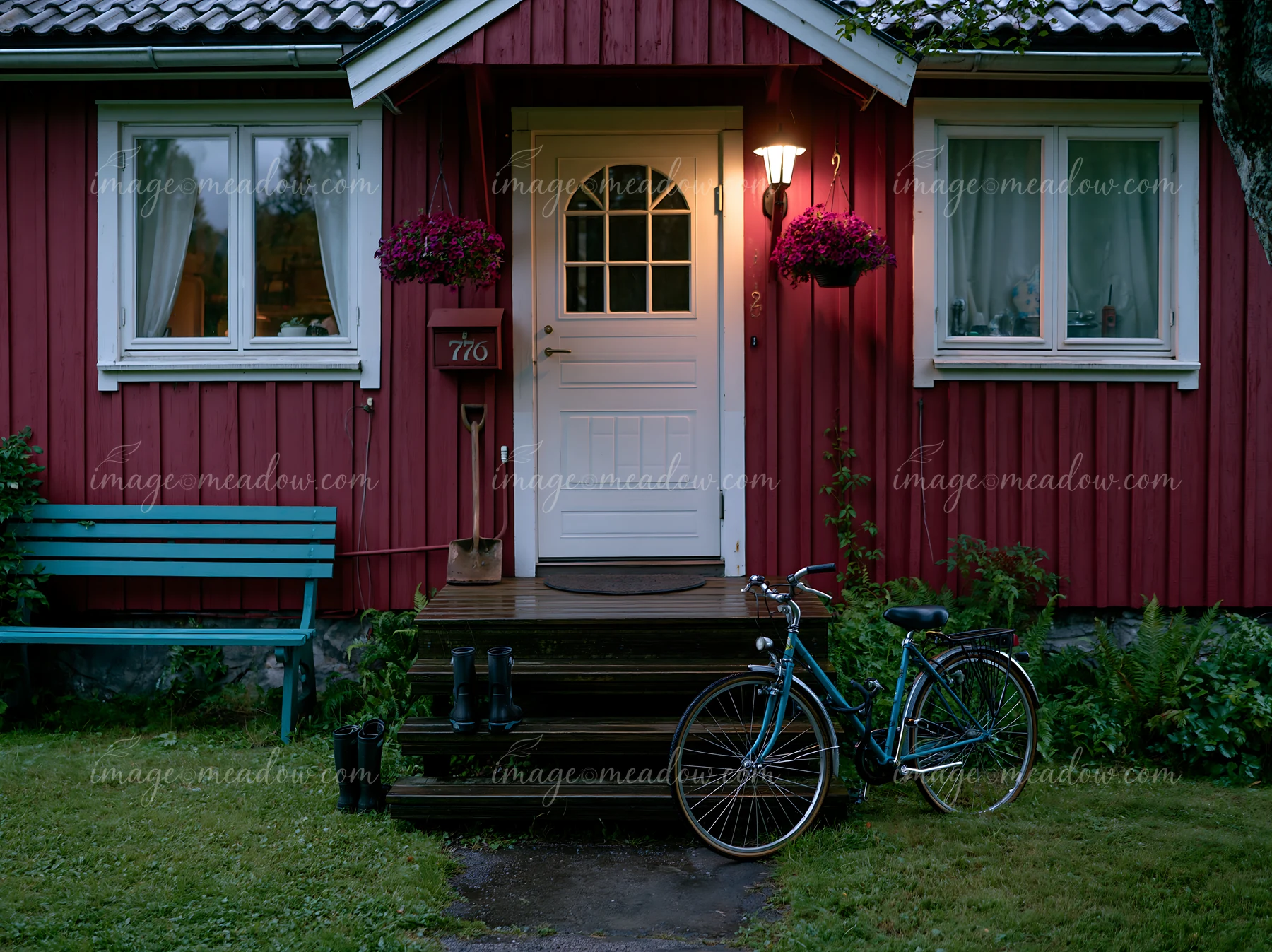 A bicycle leans against the steps of a country home surrounded by greenery.