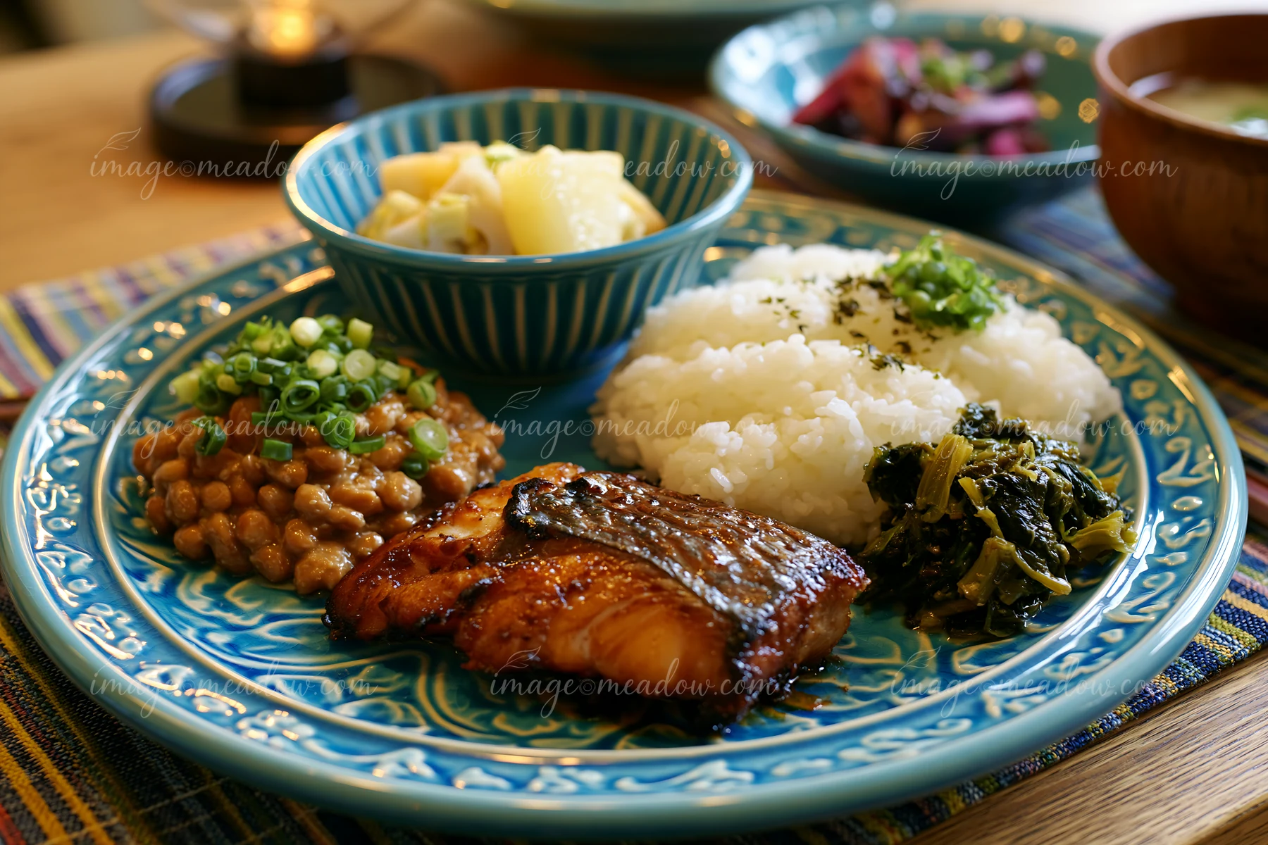 A breakfast plate with Japanese breakfast includes grilled fish, rice, soybeans, and vegetables.