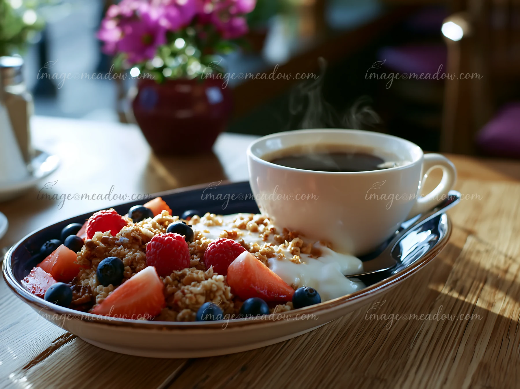 A breakfast plate with muesli, yogurt, fresh fruit, and a cup of black coffee is served on a wooden table.