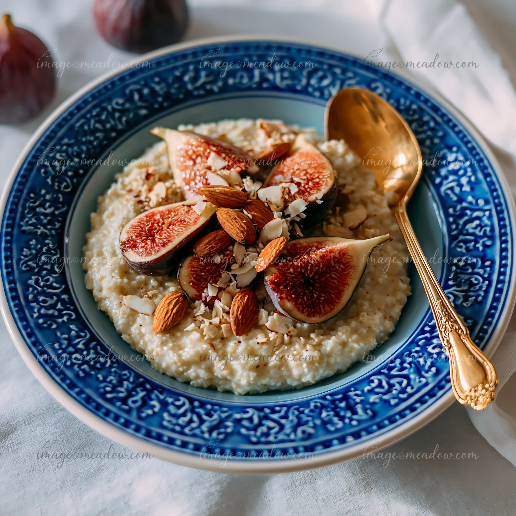 A breakfast plate with oatmeal features fresh figs, almonds, and coconut flakes on a blue decorative plate.