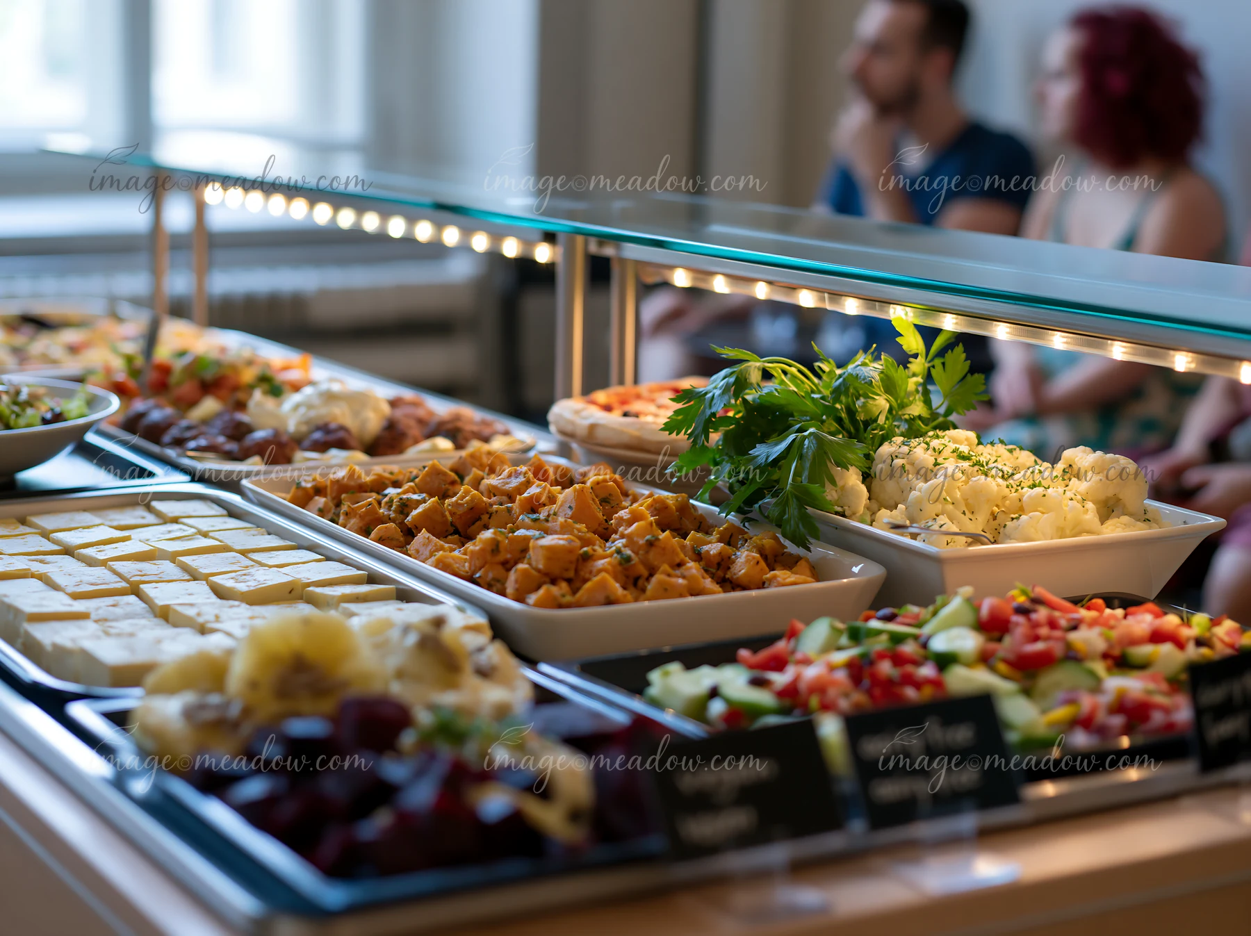 A buffet with dietary labels displays a variety of dishes for guests in a well-lit room.