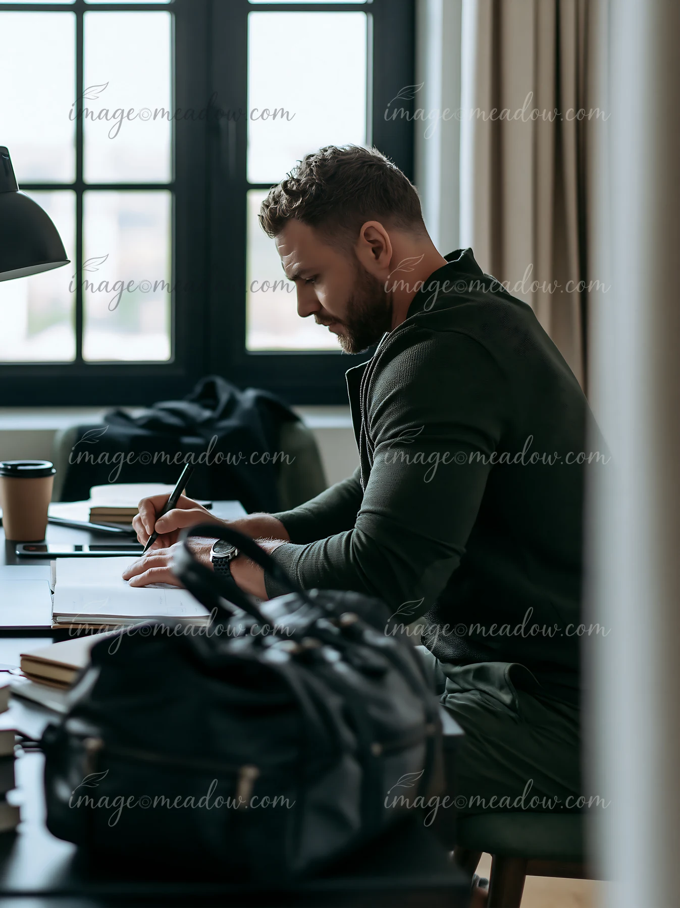 A businessman writes down his career goals at a desk in a well-lit room.