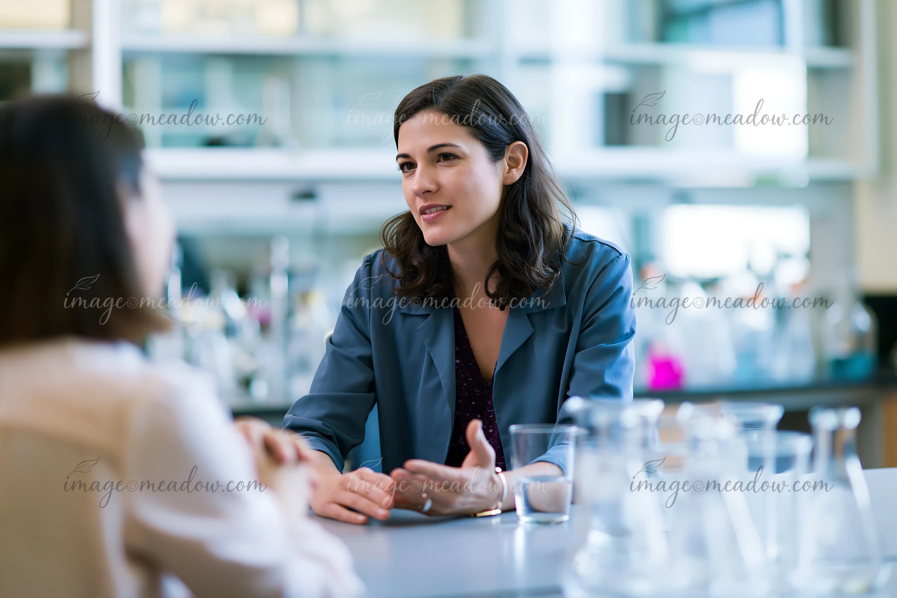 A businesswoman talks with an employee in a lab setting.