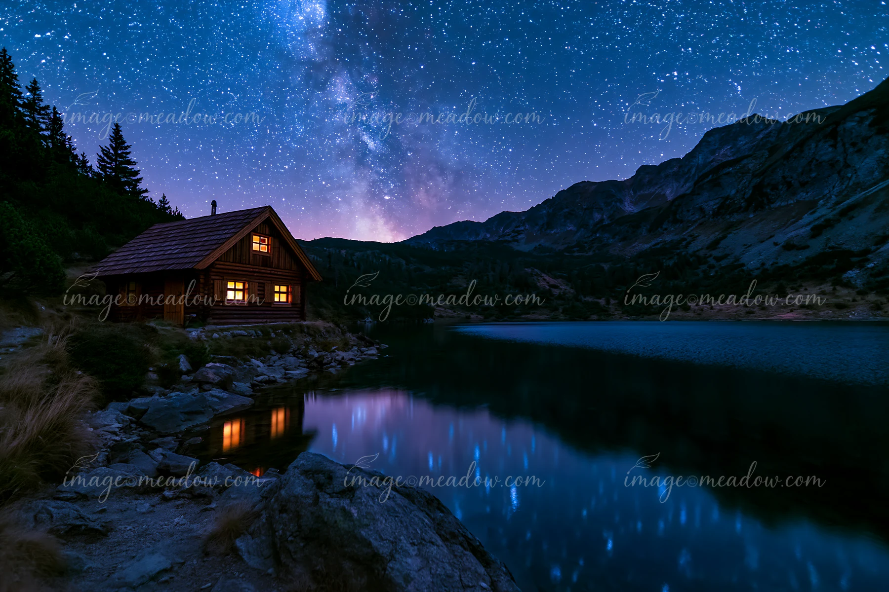 A cabin sits quietly by a lake under a starry night sky with the Milky Way visible.