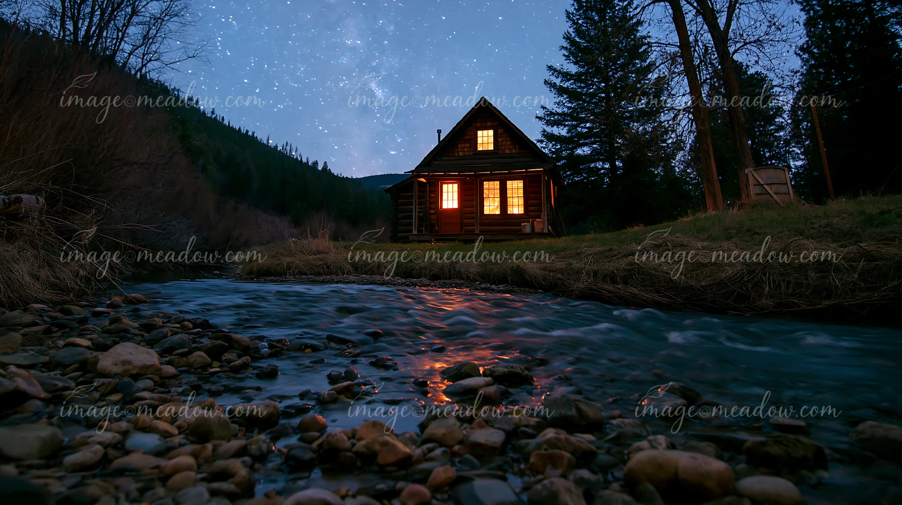 A cabin stands beside a clear stream, illuminated by stars in the night sky.