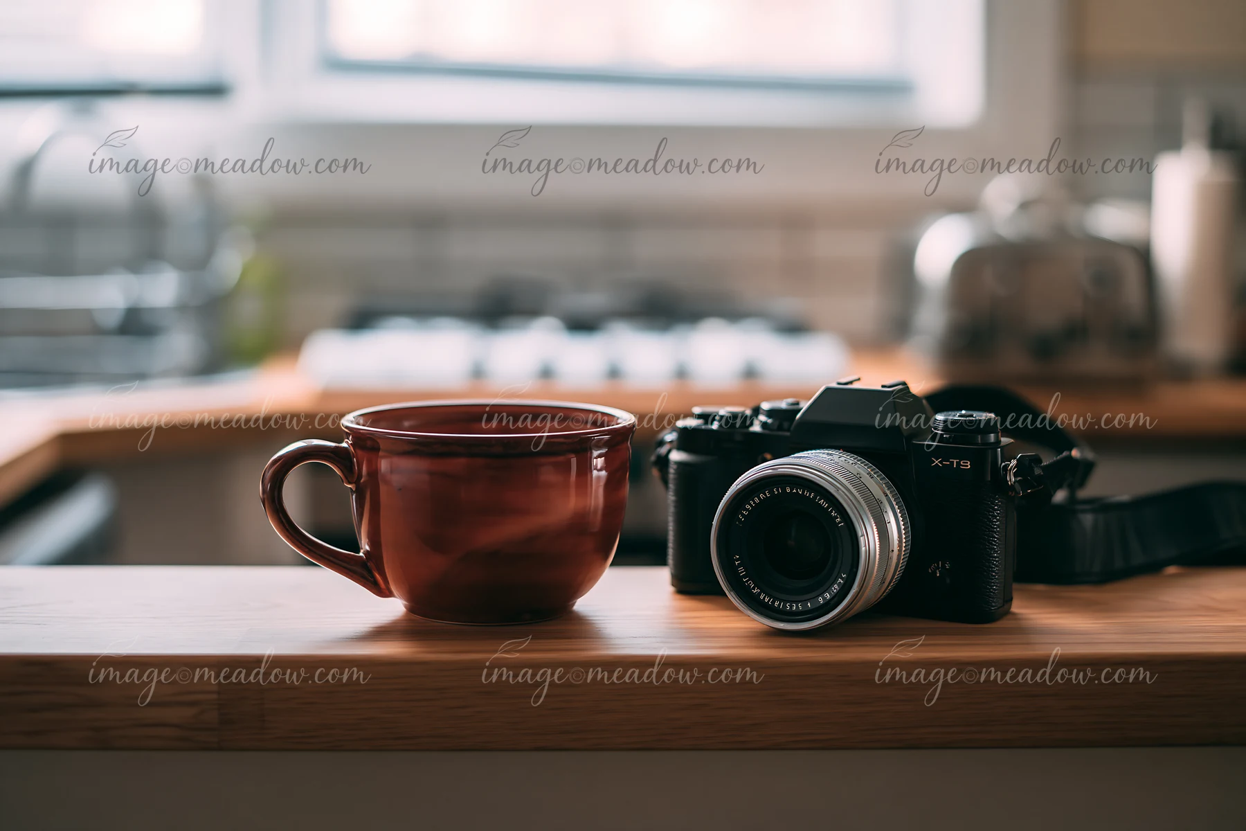 A camera and lens on a wooden shelf sit next to a brown coffee cup in a kitchen setting.