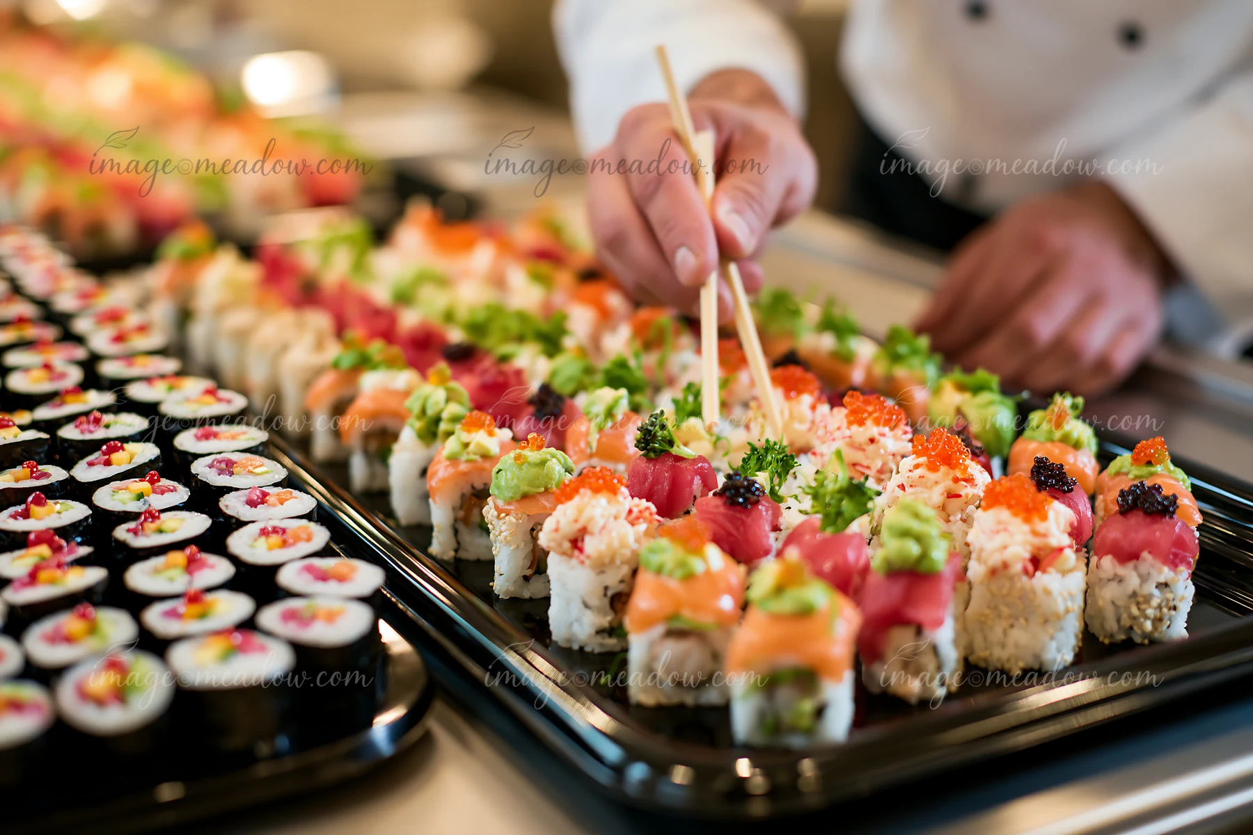 A chef arranges sushi on a large platter at a catering event.