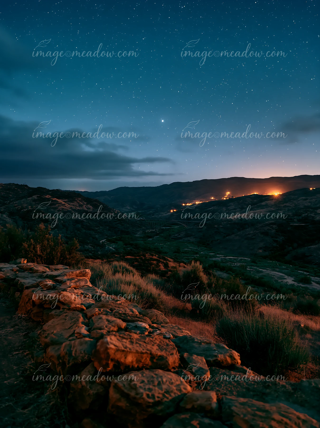 A clear night sky filled with stars shows a mountain valley.
