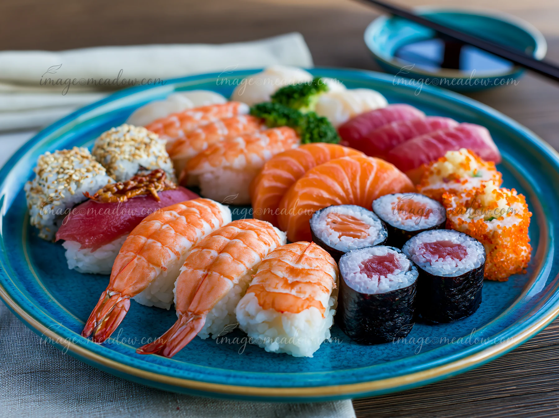 A close-up view of a modern sushi presentation featuring sushi rolls, nigiri, and sashimi arranged on a blue plate.