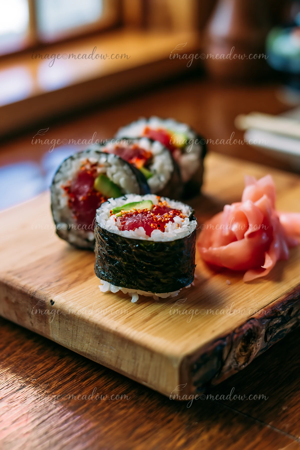A close-up view of a spicy tuna roll served on a wooden platter.